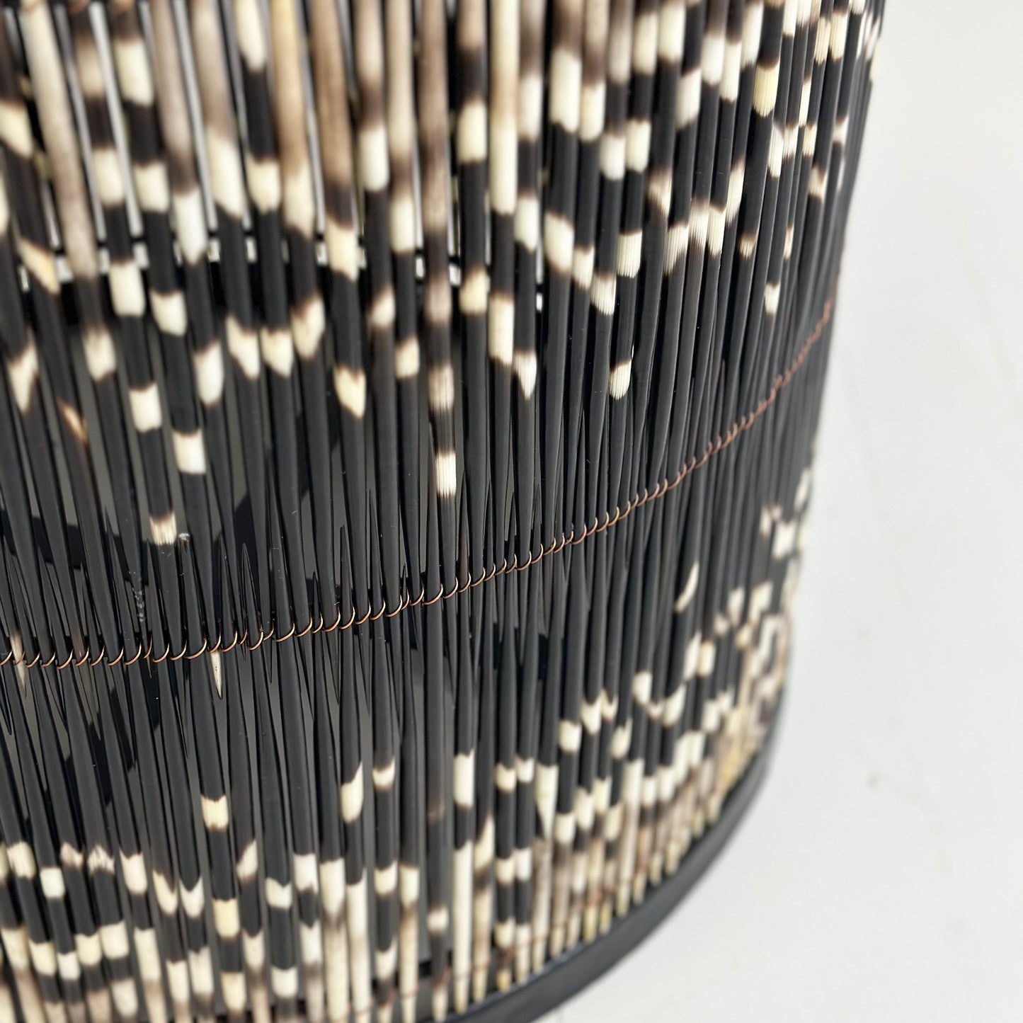 A round porcupine quill table with black and white quills, placed on a neutral background.