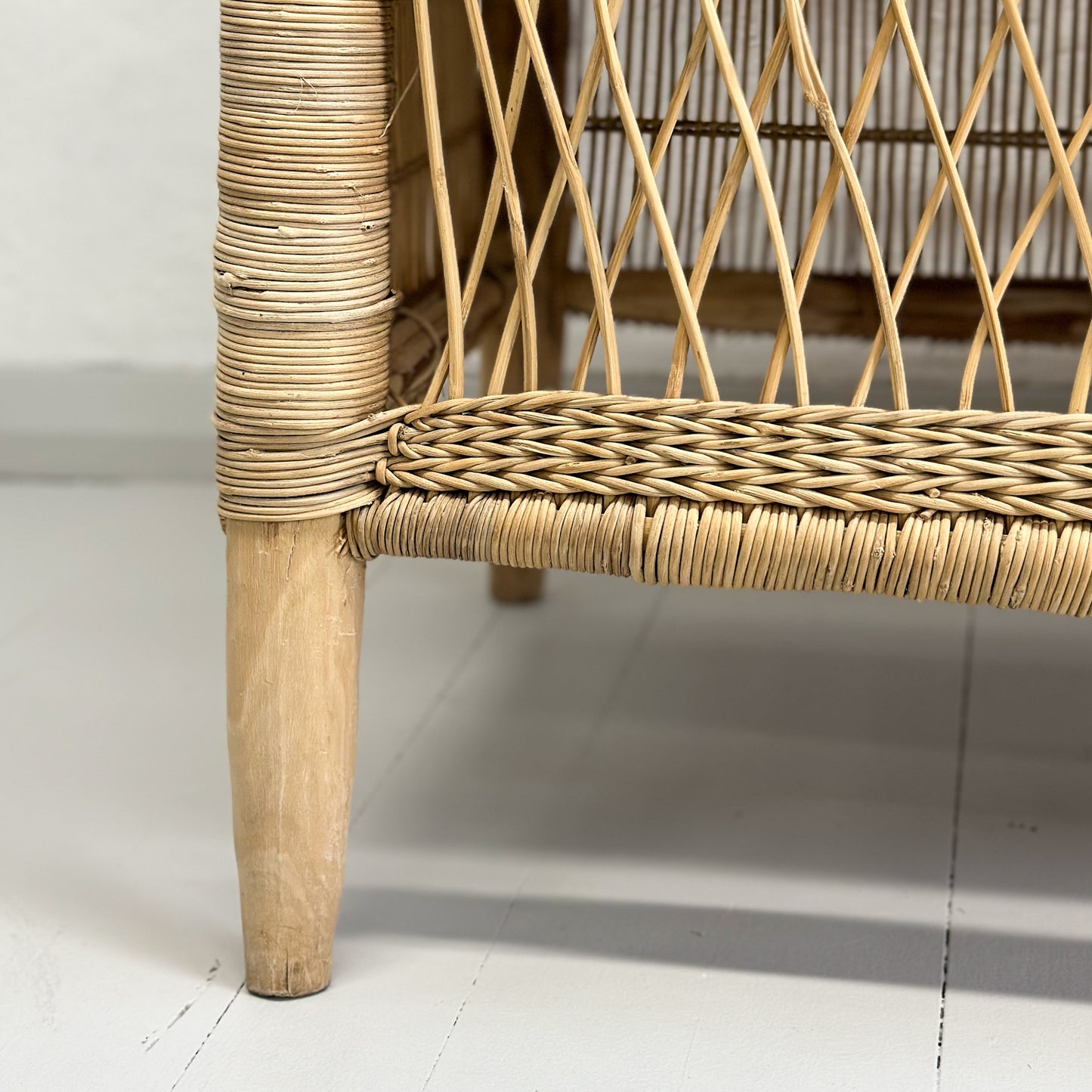 A beige cane loveseat sofa with a solid pattern and no visible cushions.