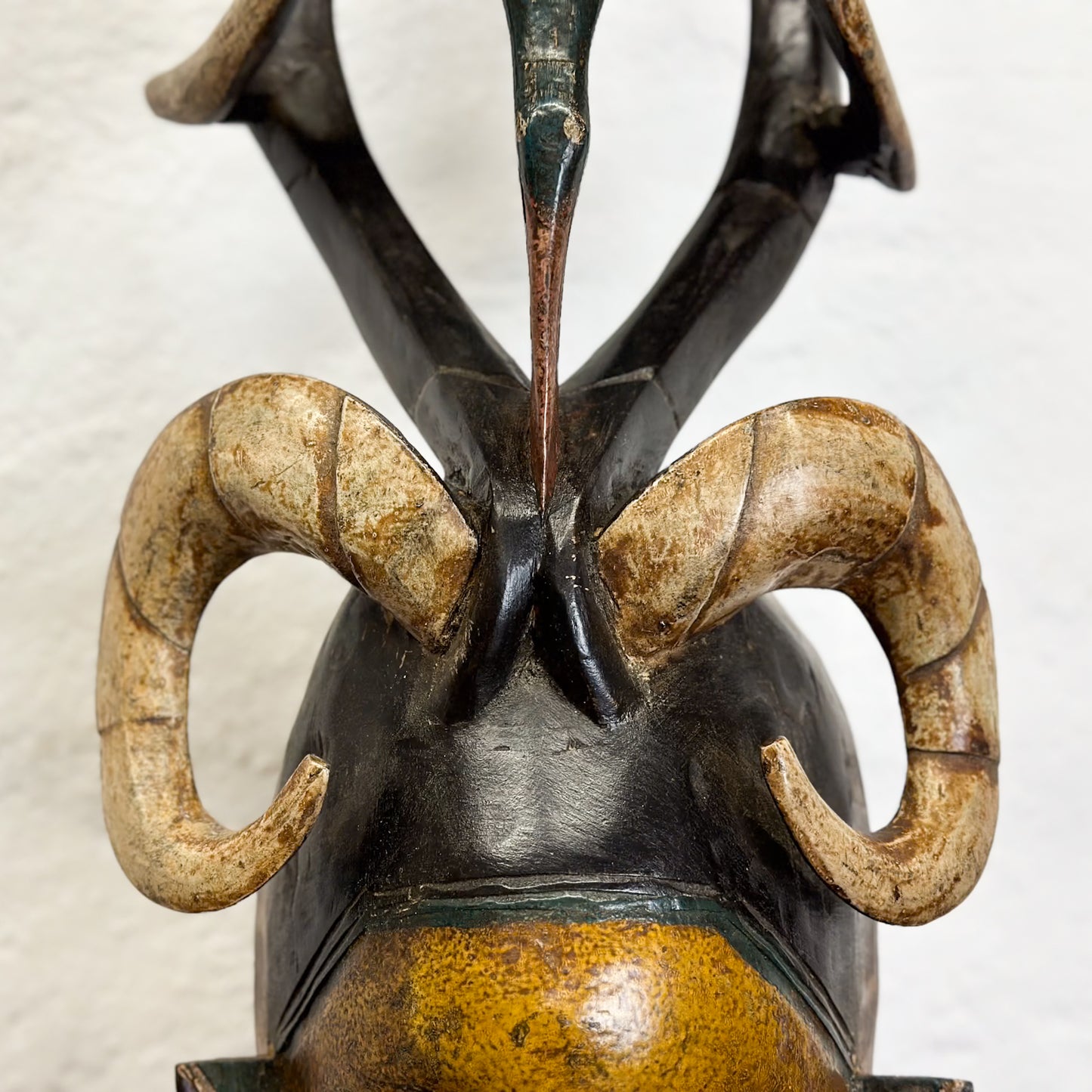 A wooden and ivory Guro mask with geometric and spiritual symbolism, displayed on a stand against a plain background.