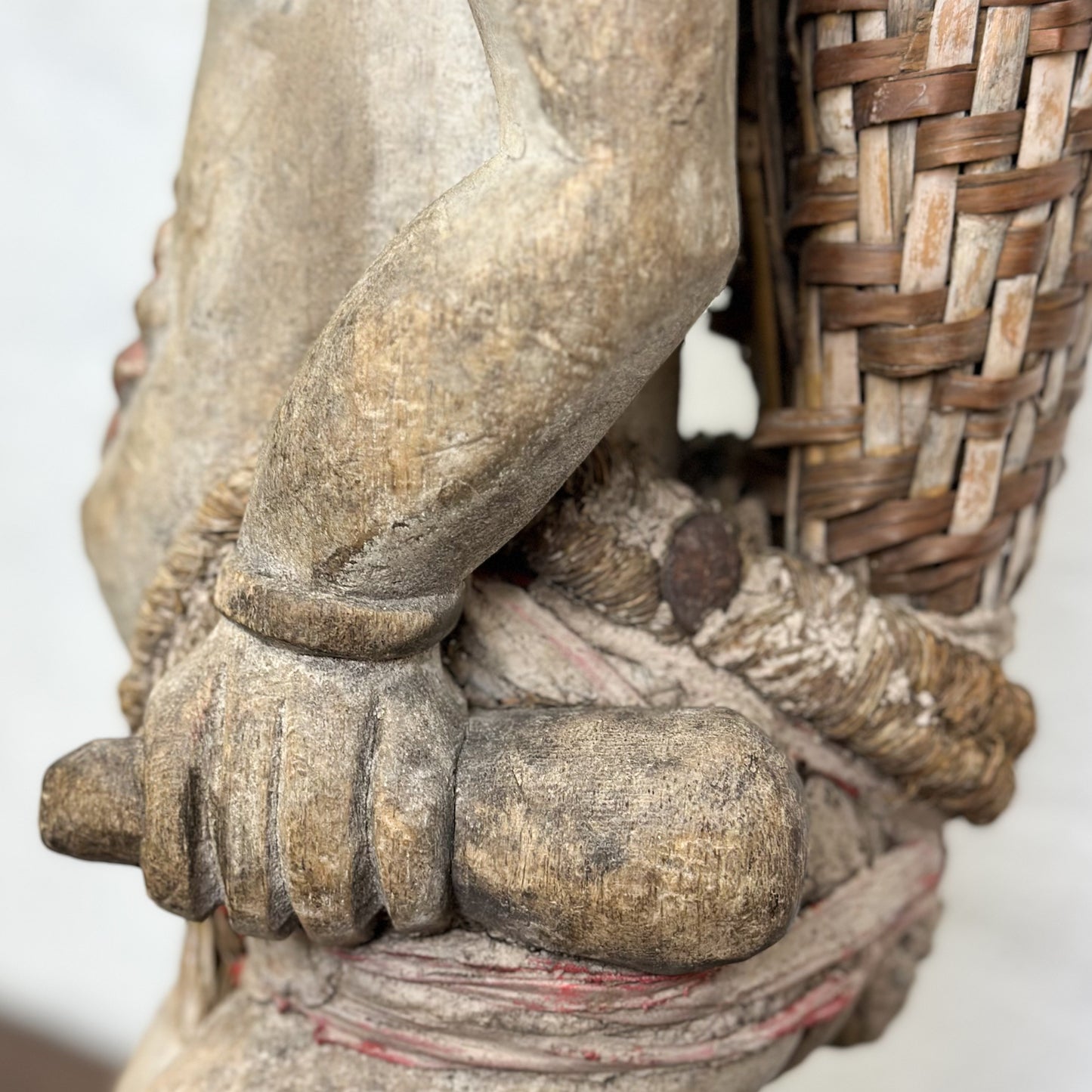 A wooden sculpture of a vintage Punu figure with a basket, featuring a simple yet expressive face, standing against a neutral background.