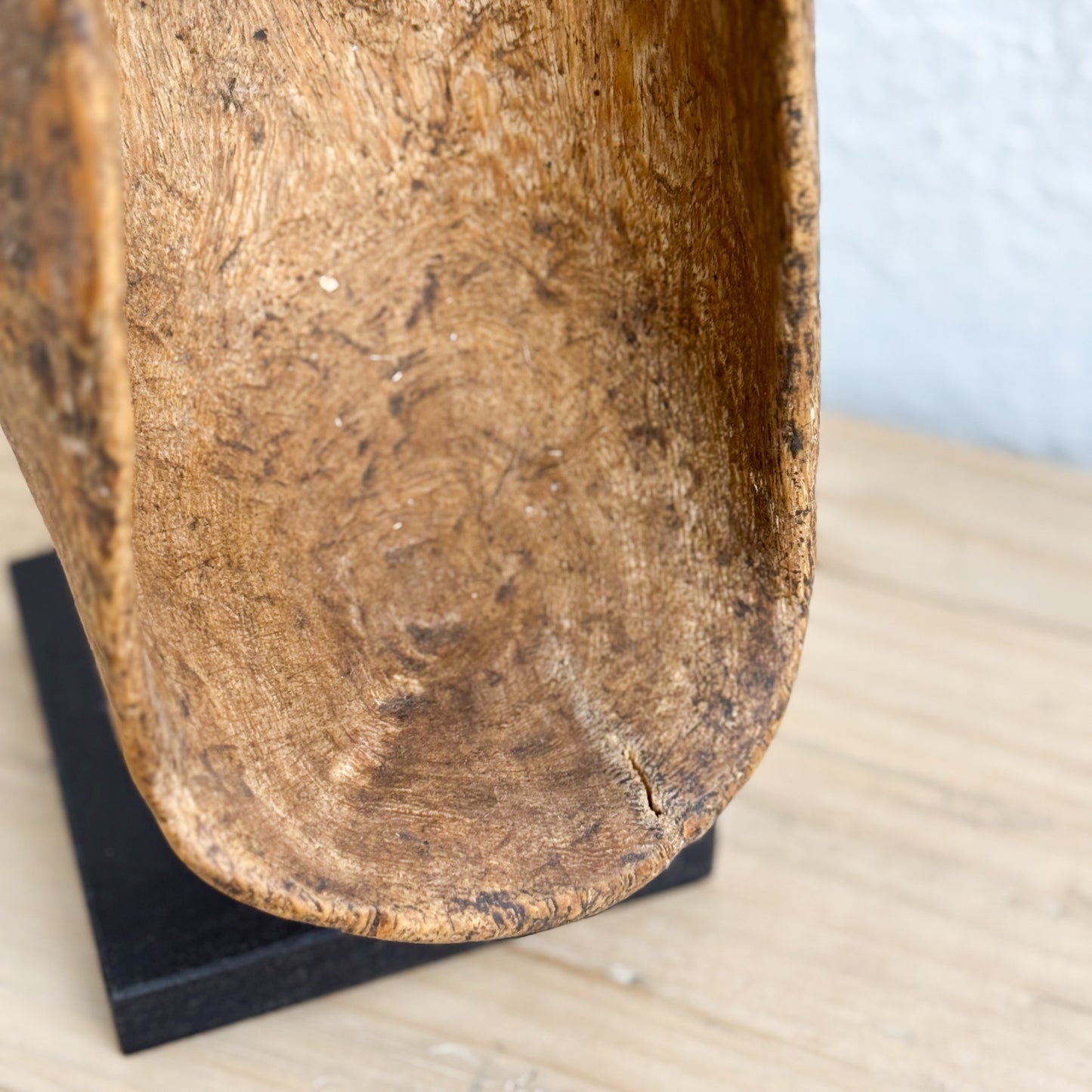 Close-up of a wooden bowl on a stand with a light background