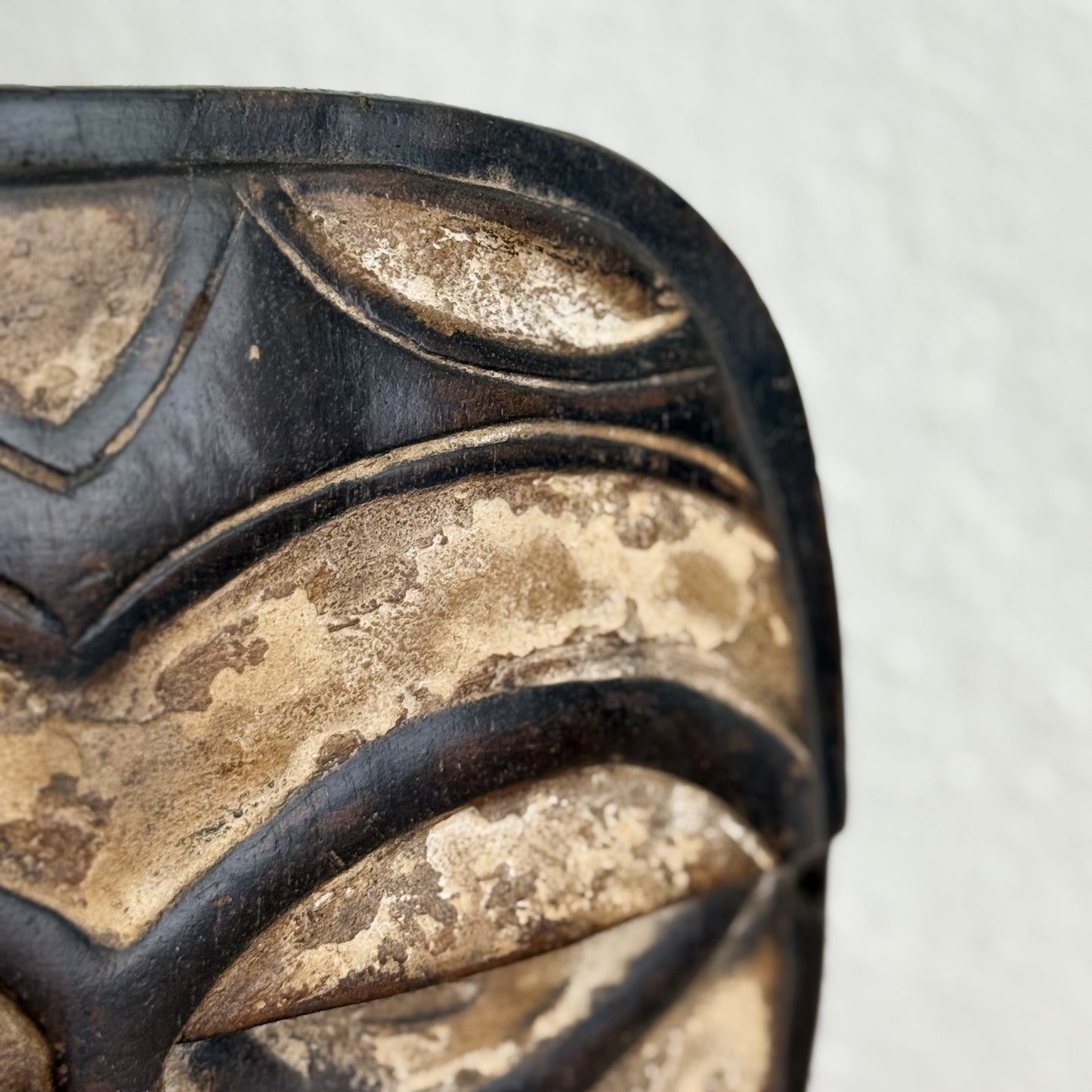 Close-up of a wooden mask with intricate carvings on a white background