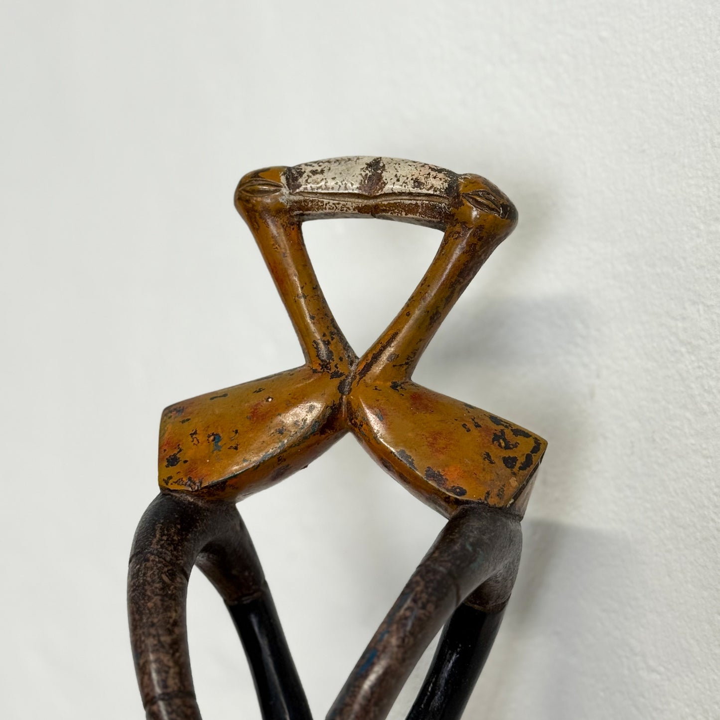 Vintage metal bottle opener with a cross-shaped design on a white background