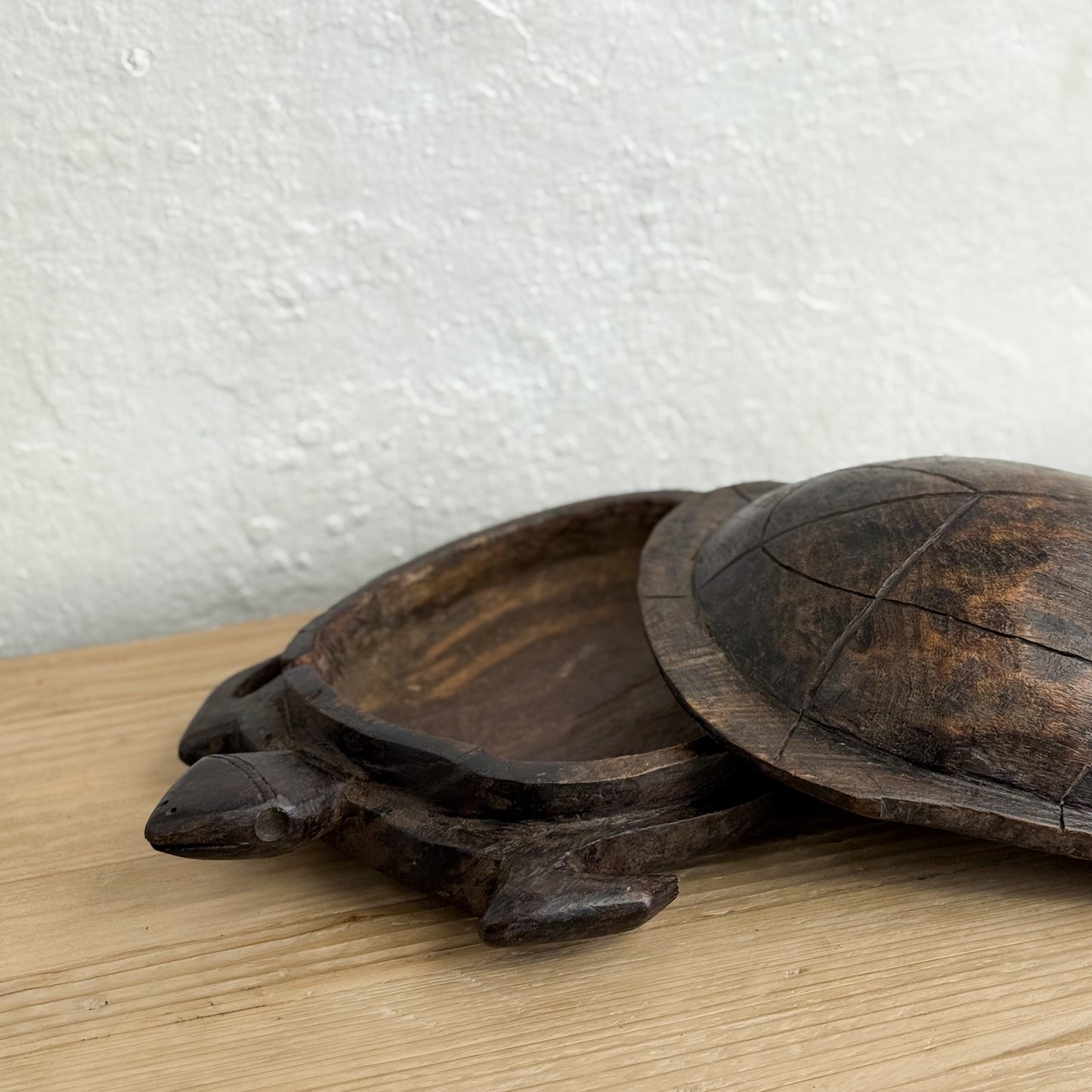 Wooden turtle-shaped trays on a wooden surface with a white textured background