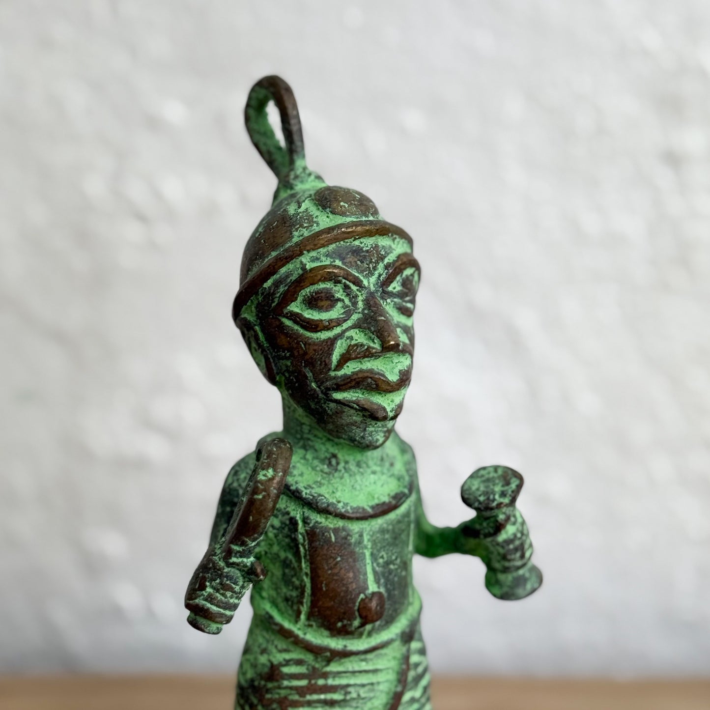 Green patinated metal figurine of a warrior on a white background