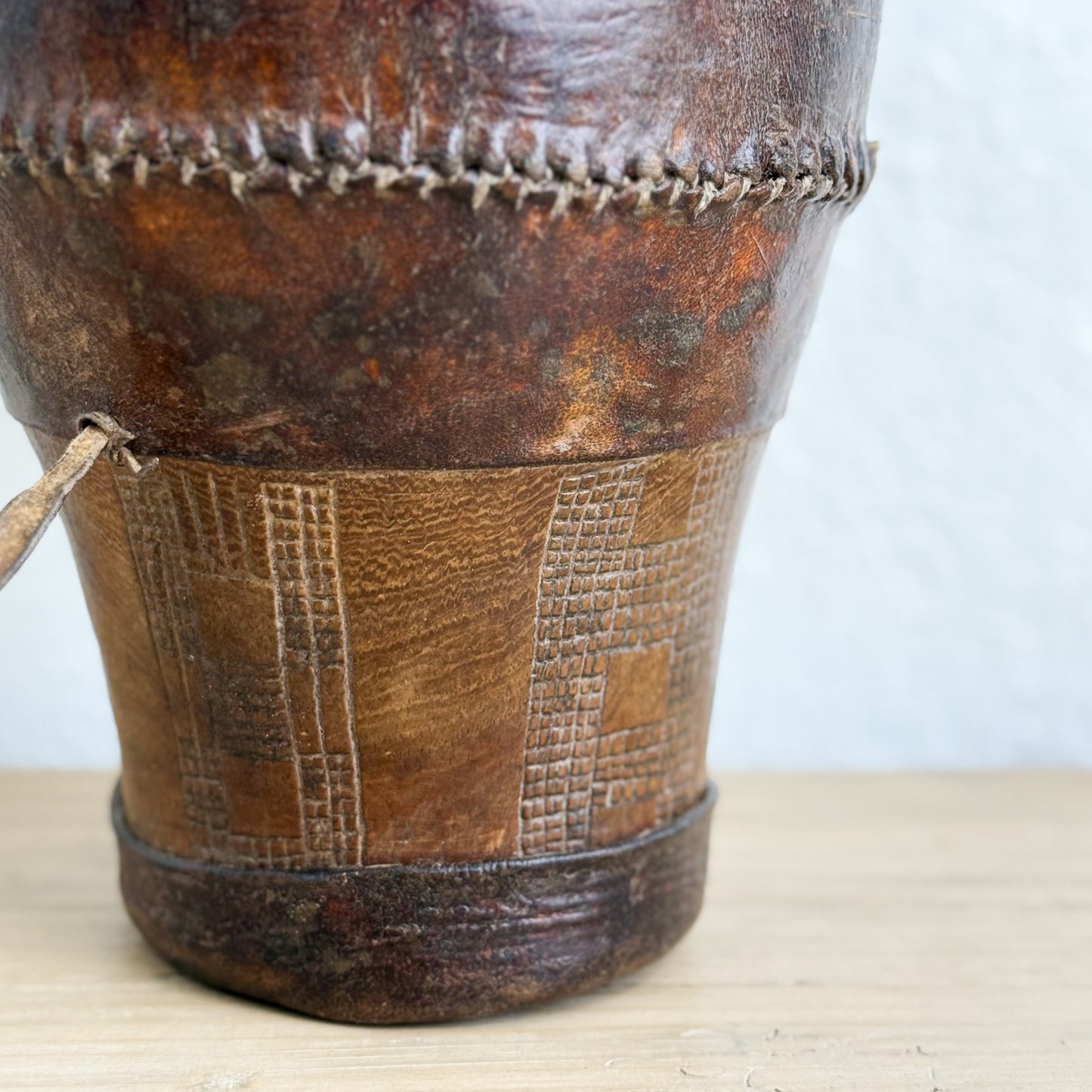 Close-up of a brown leather bag with visible stitching on a light background
