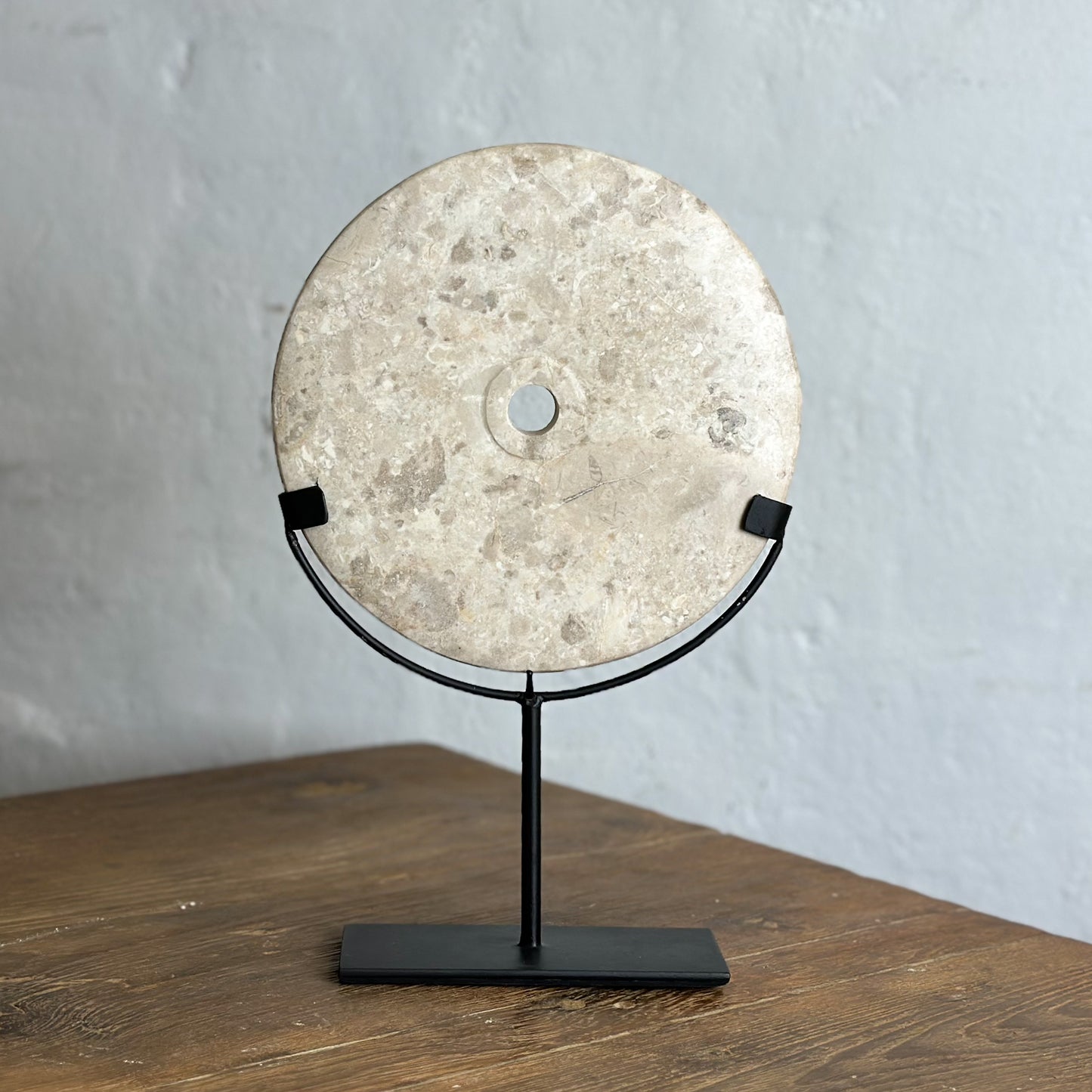 Three round natural stone discs on black stands, displayed against a neutral background.