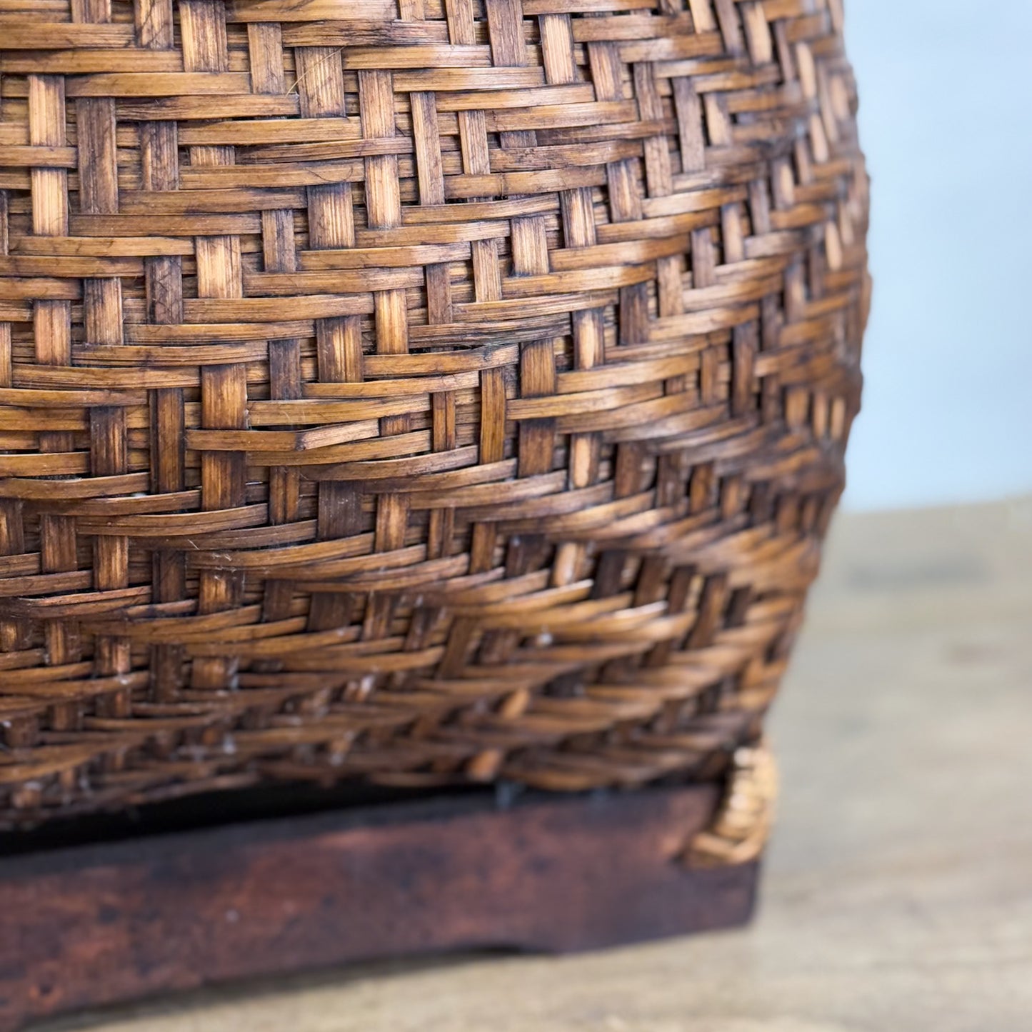 A brown wicker basket with a lid, placed on a wooden surface against a white background.