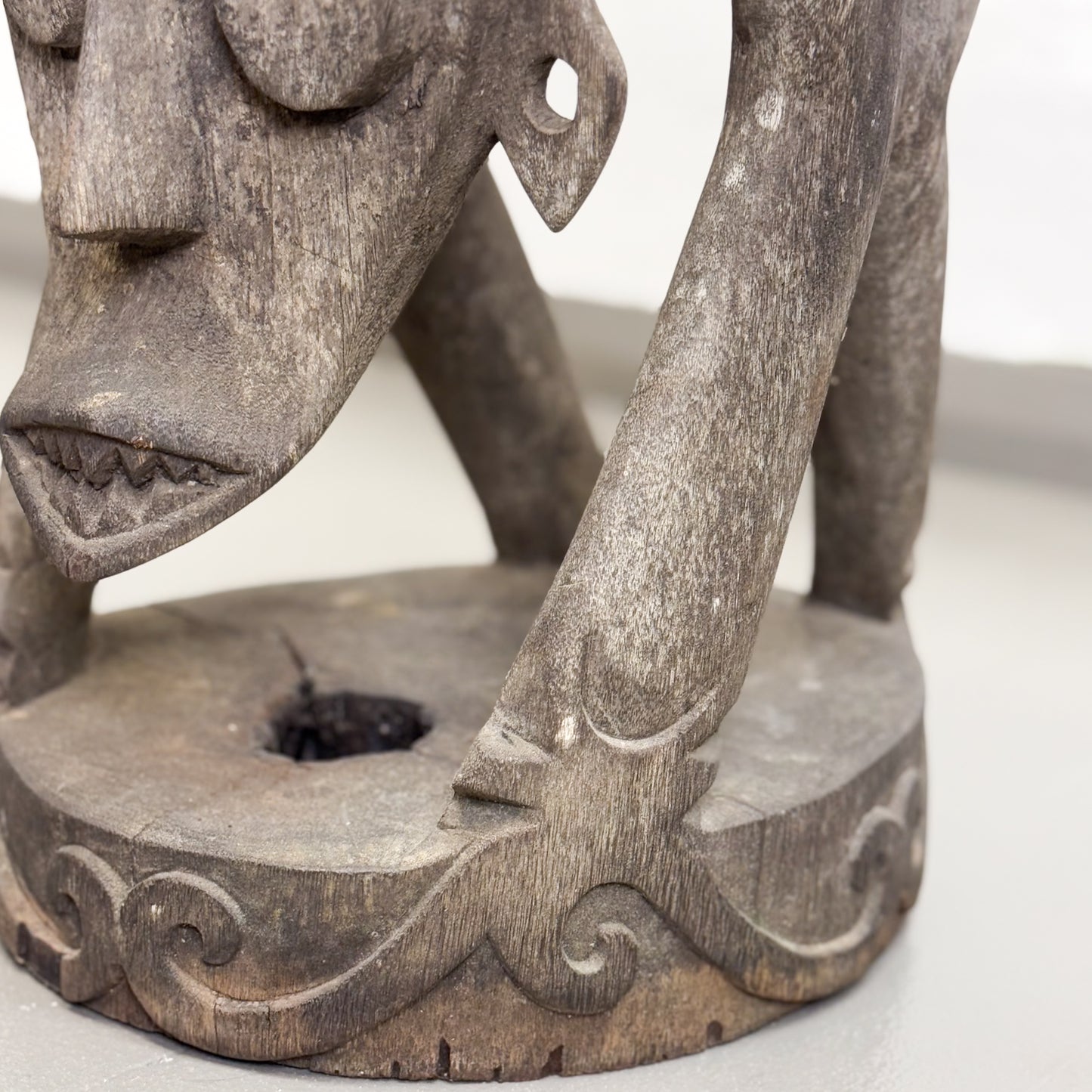 A carved wooden stool with a tribal design representing a face on the island of Borneo.