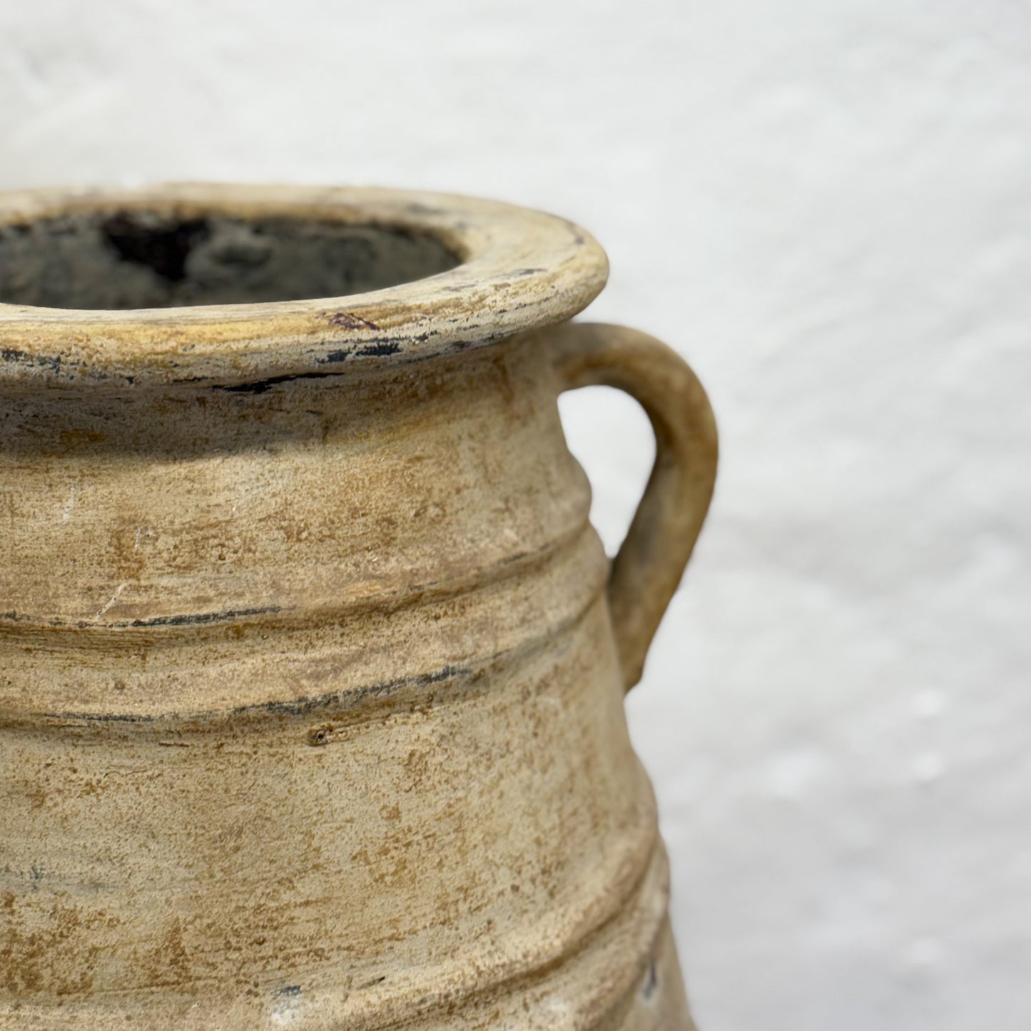 A beige terracotta pot with handles, displayed against a white background.