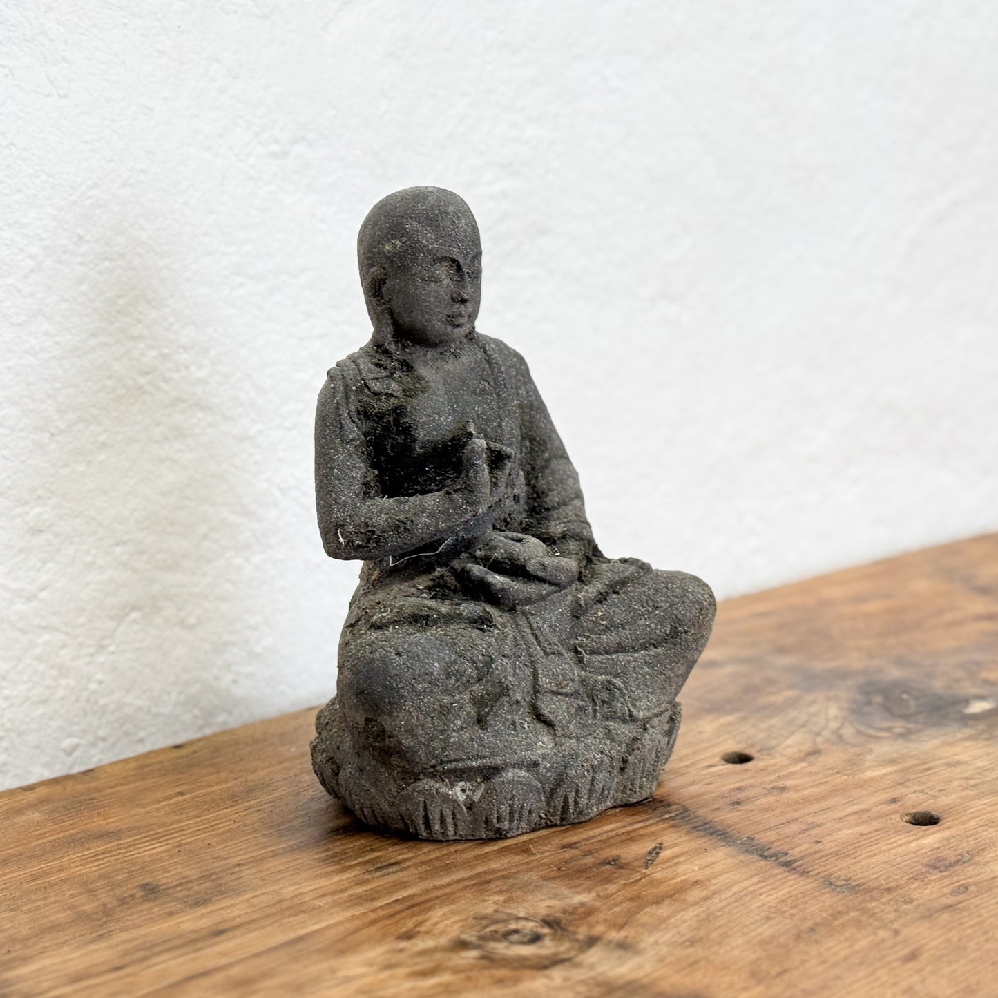 Black stone statue of a seated figure on a wooden surface