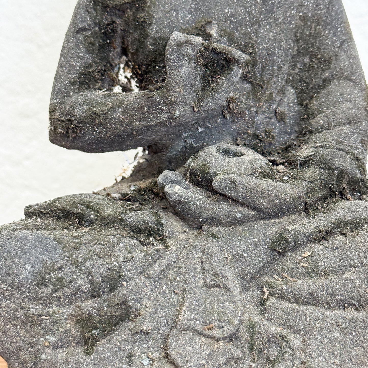 Close-up of a stone sculpture with hands holding a ball on a sandy background