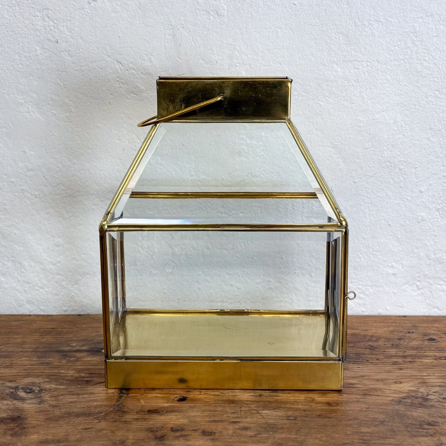 Gold lantern with glass panels on a wooden surface and white background