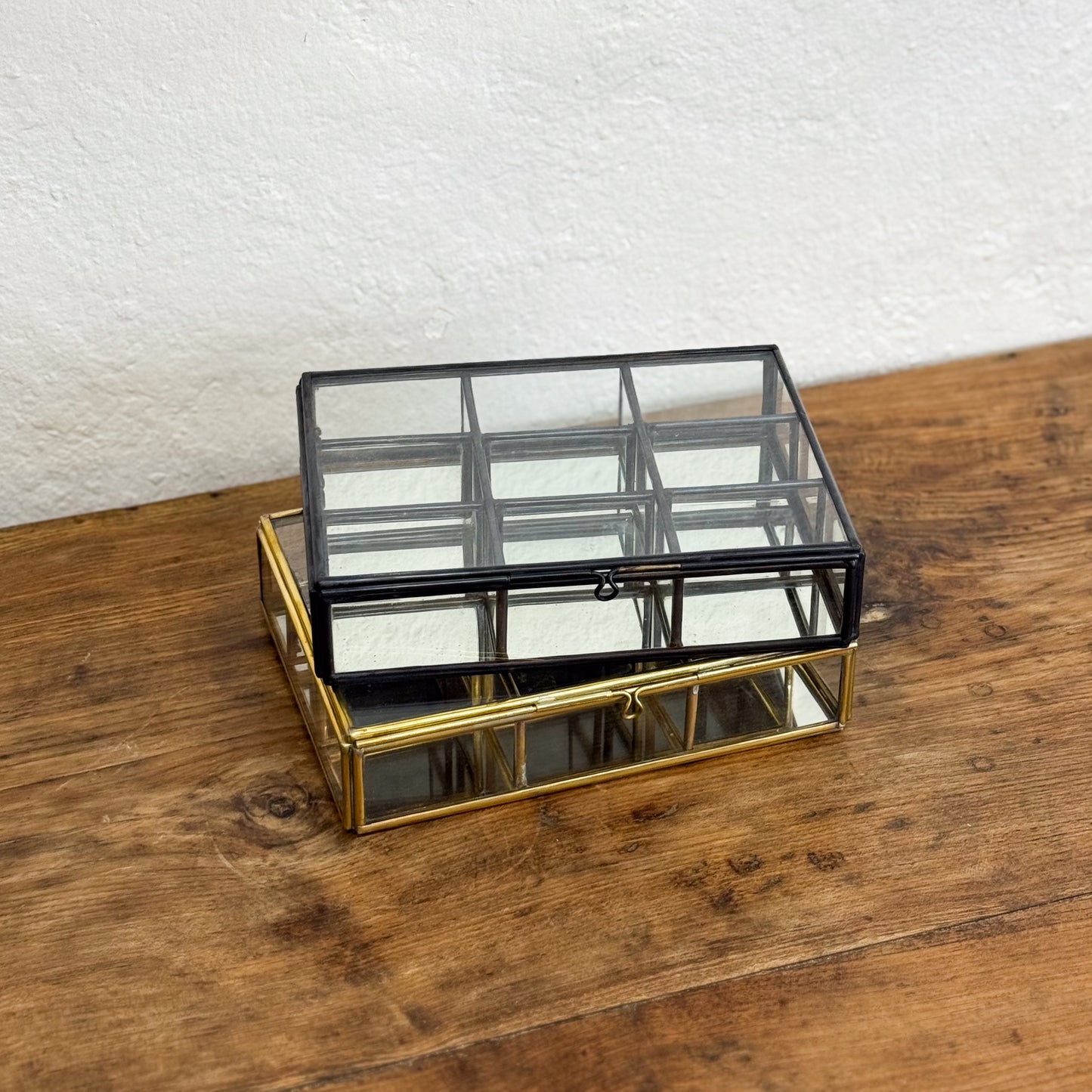 Glass jewelry box with gold frame on a wooden surface