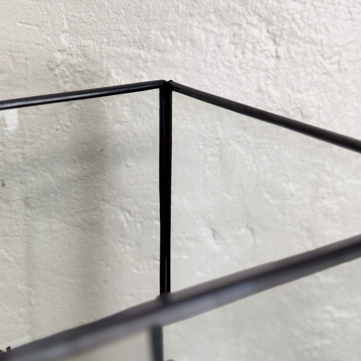 Black metal frame against a textured white wall