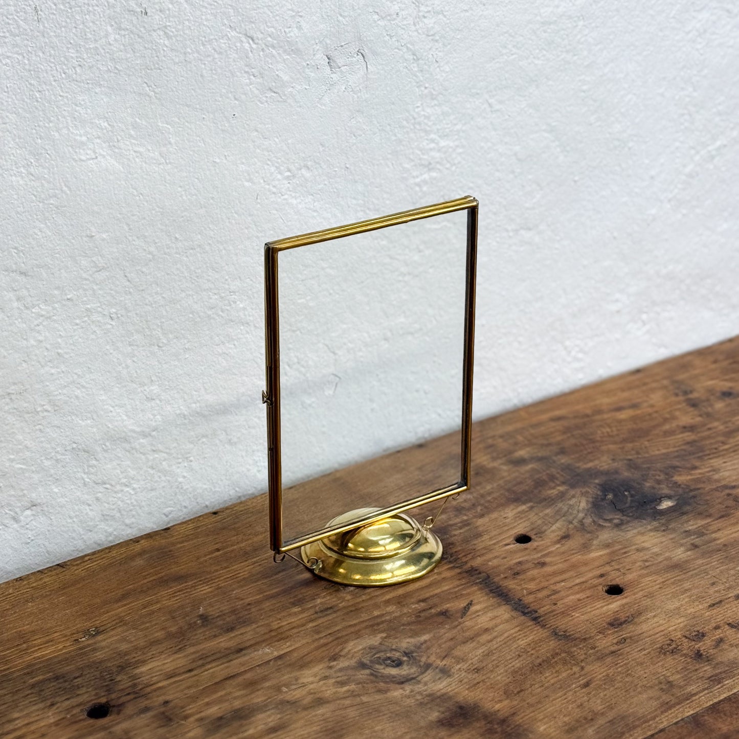 Gold metal stand on a wooden surface with a white textured wall background