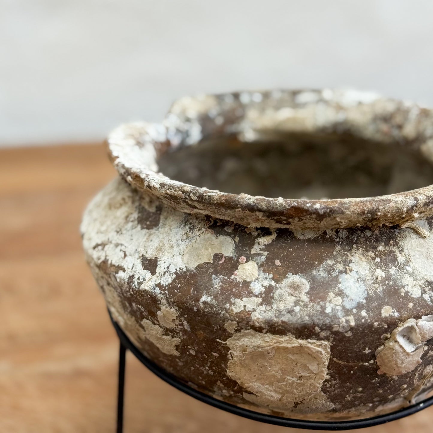 Vintage-style terracotta pot on a stand with a blurred background