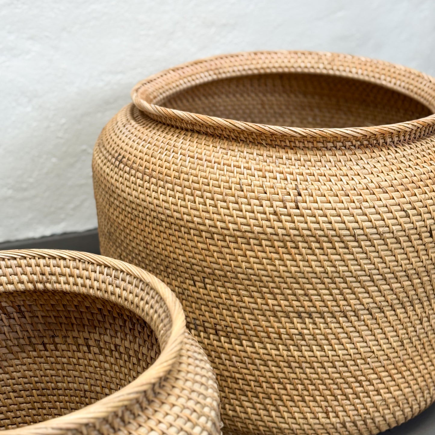 Two woven baskets with a textured surface on a neutral background