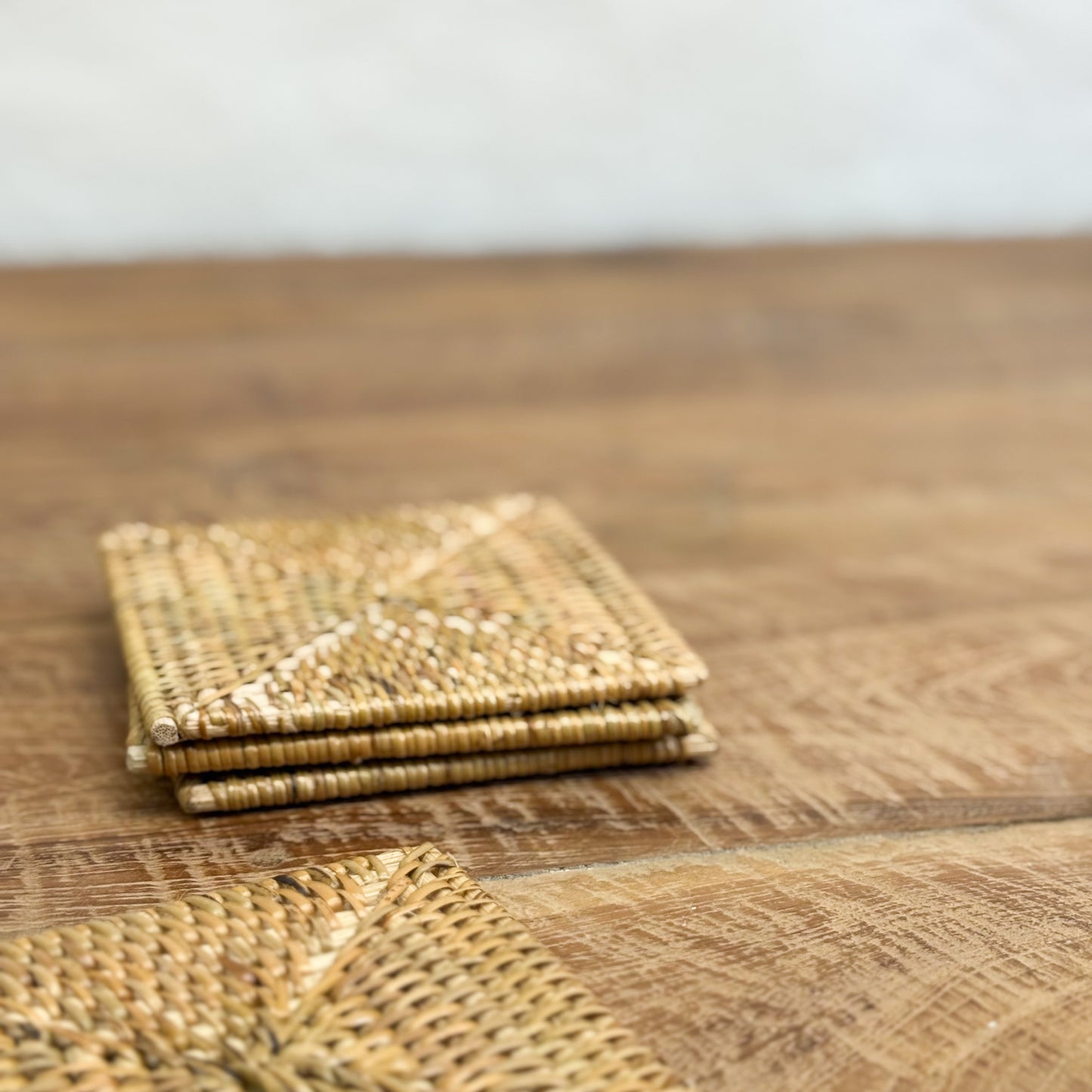 Stack of woven coasters on a wooden surface
