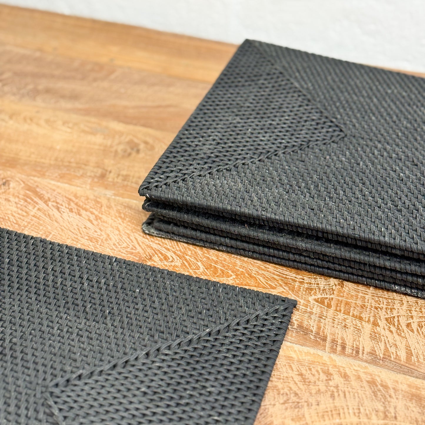 Stack of black textured mats on a wooden surface