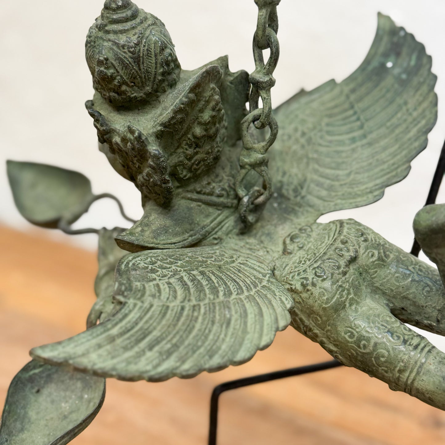 Bronze statue of a winged creature with intricate details on a stand.