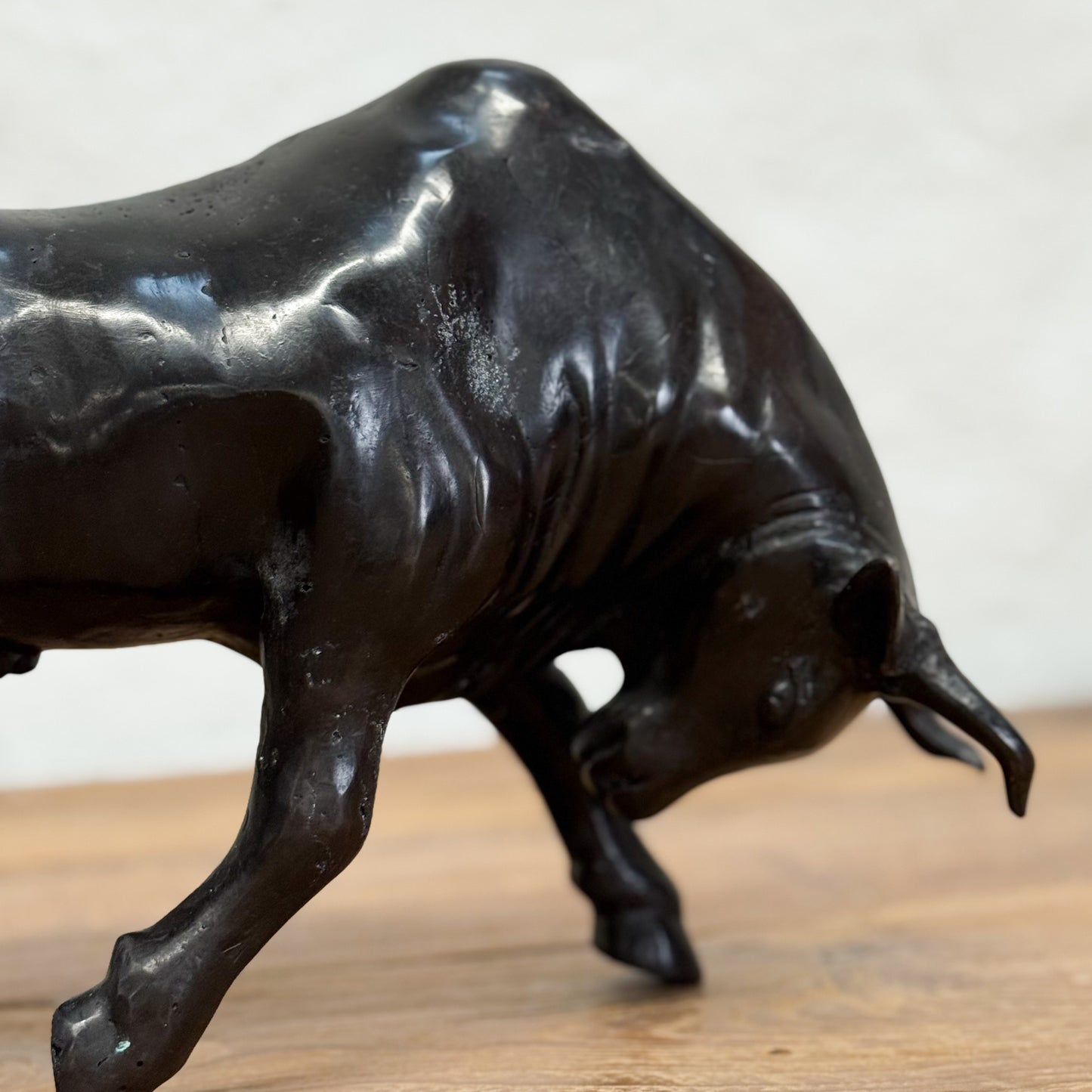 Bronze bull sculpture on a wooden surface with a neutral background