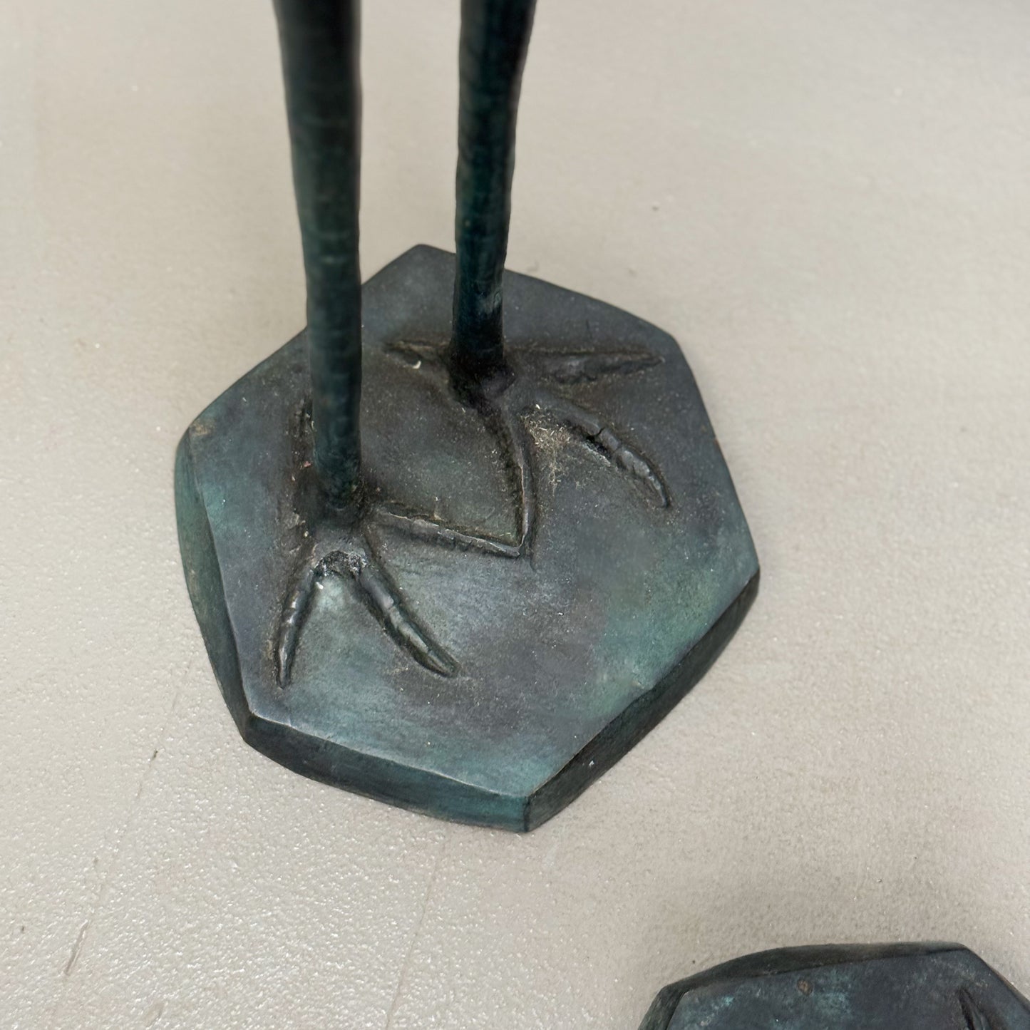 Bronze sculpture of a figure on a hexagonal base against a light background