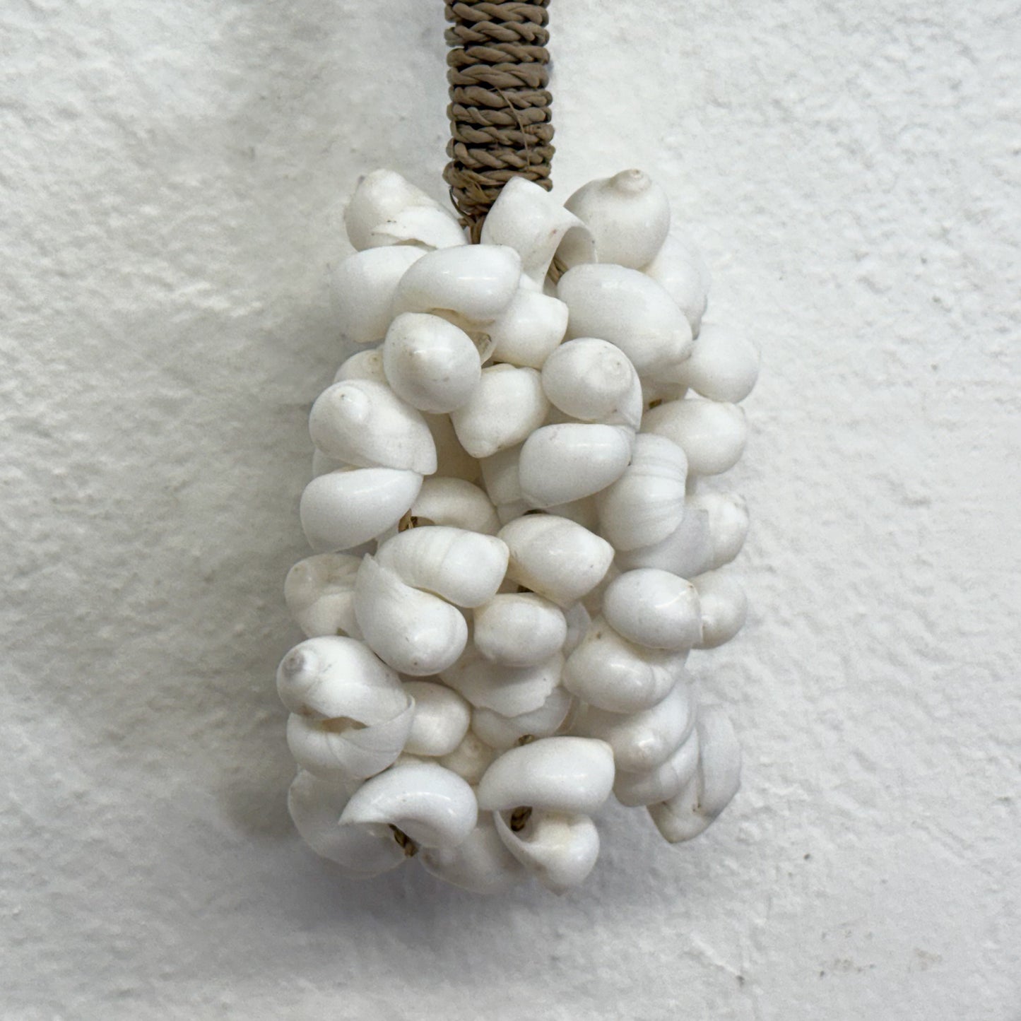 White textured pendant on a rope against a light gray background