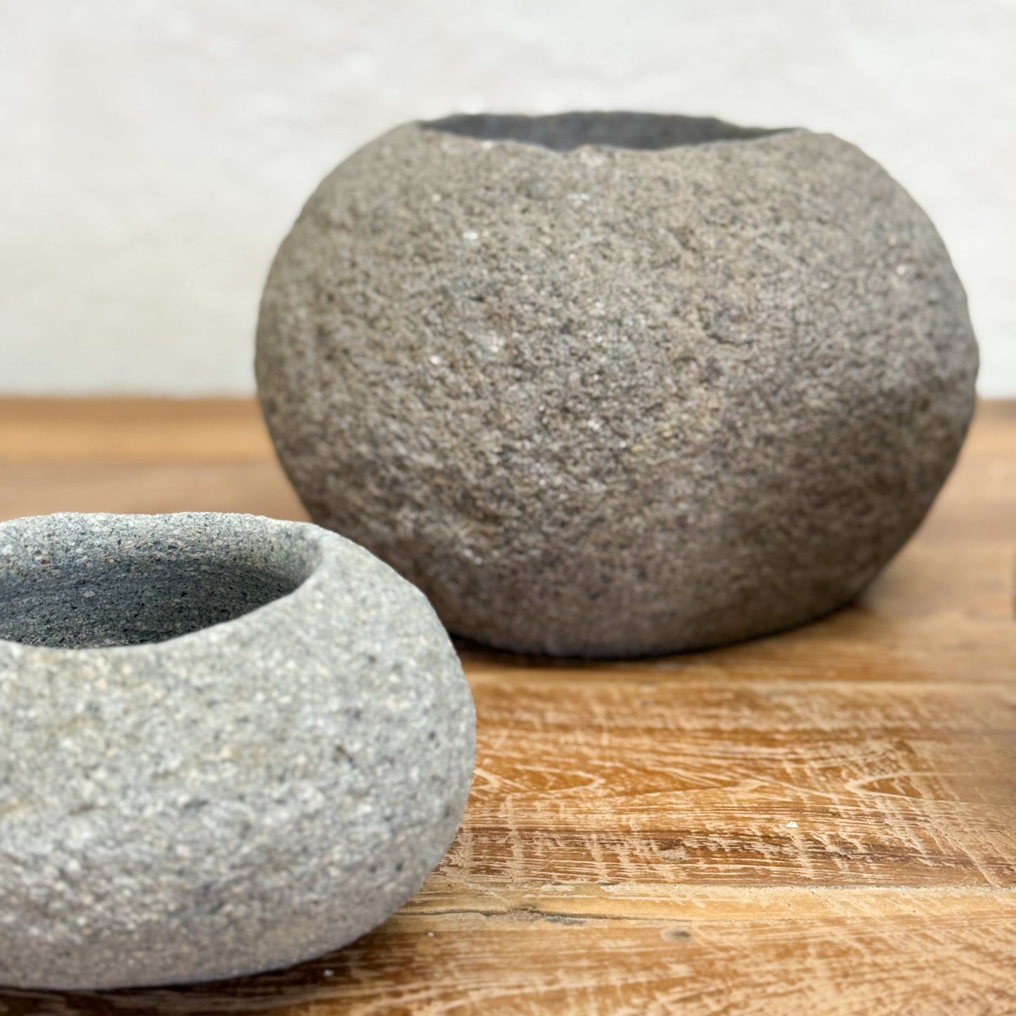 Two gray stone bowls on a wooden surface with a white background