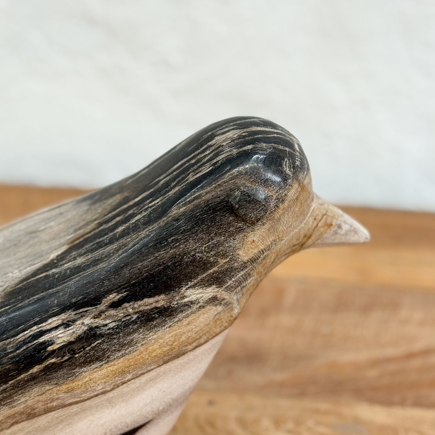 Close-up of a wooden bird sculpture on a neutral background
