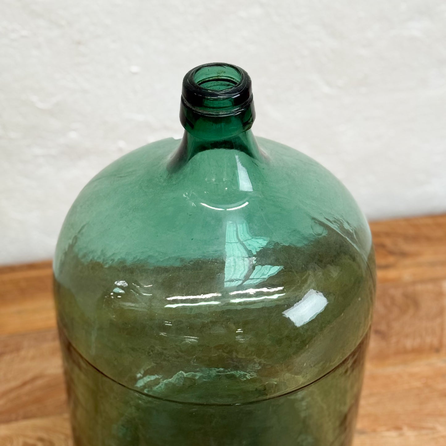 Green glass bottle on a wooden surface with a white background