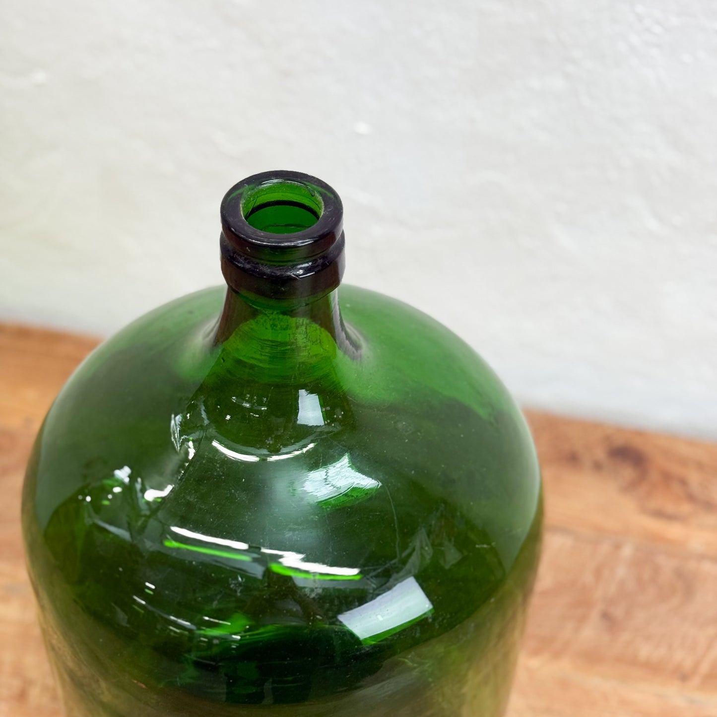 Green glass bottle with black cap on a wooden surface