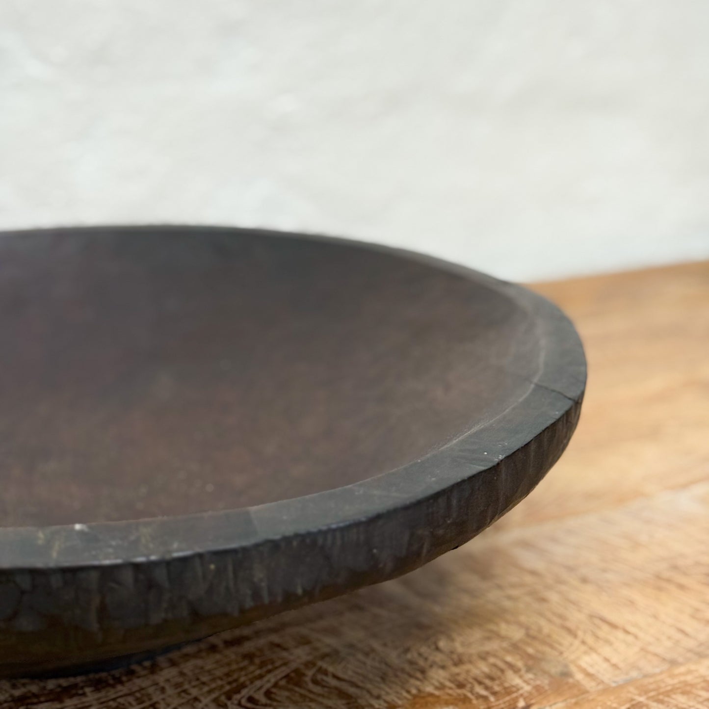 Dark wooden bowl on a wooden surface with a white background