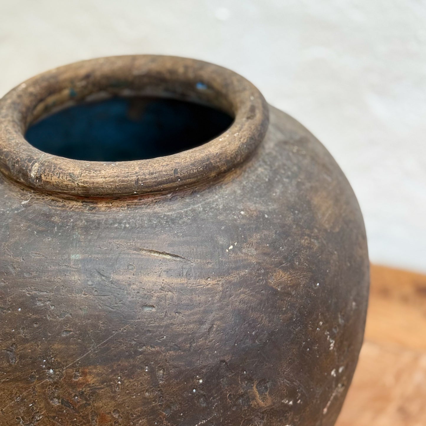 Close-up of an old, dark brown ceramic jar with a blurred background