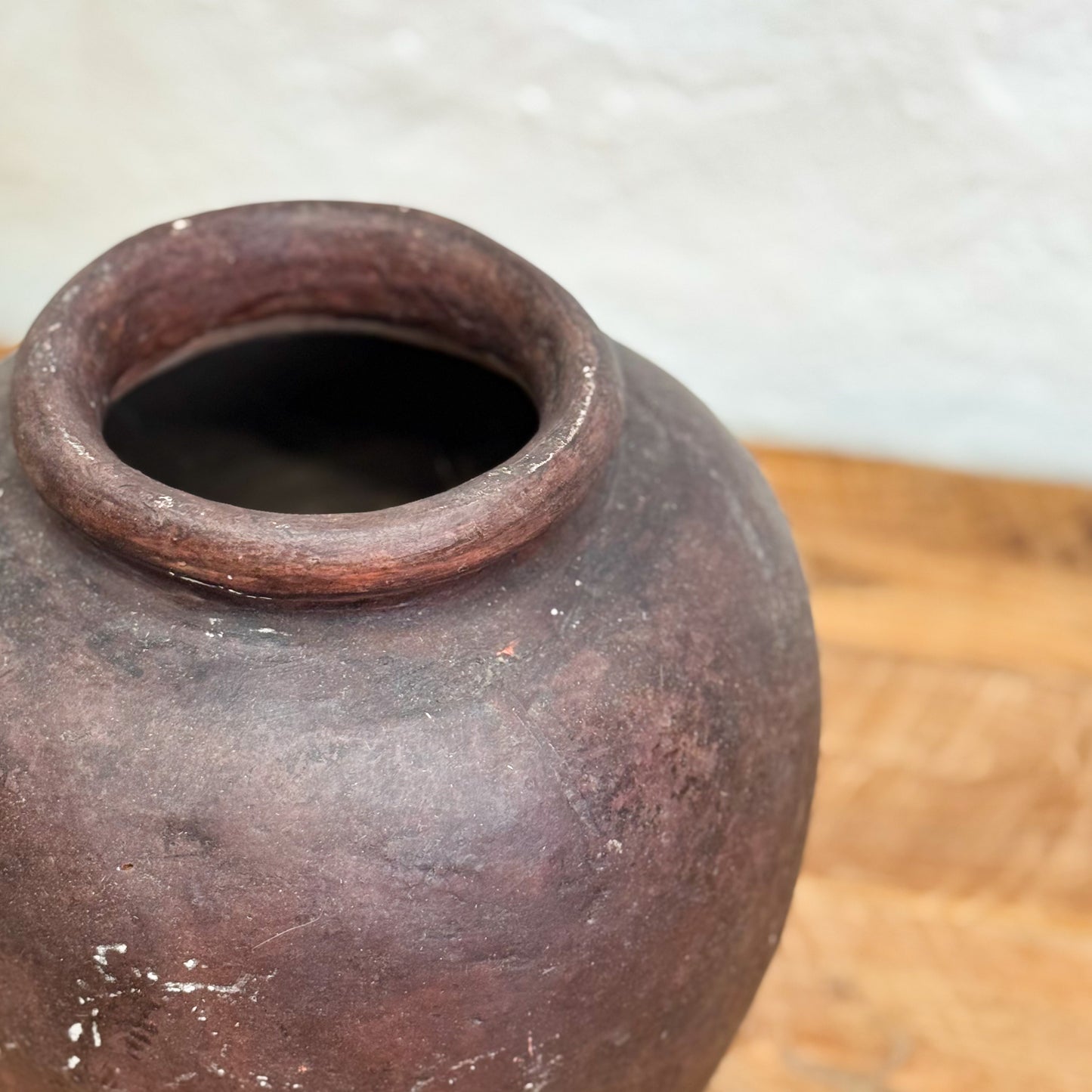 Brown ceramic pot on a wooden surface with a light gray background