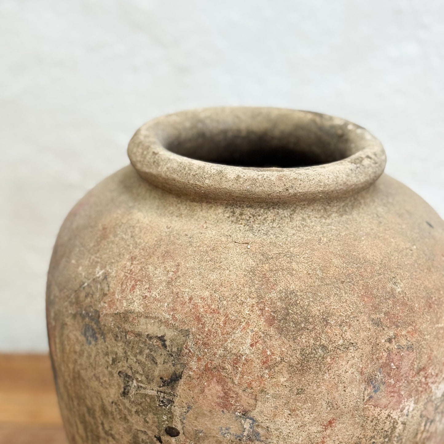 Vintage terracotta jar with a textured surface on a neutral background