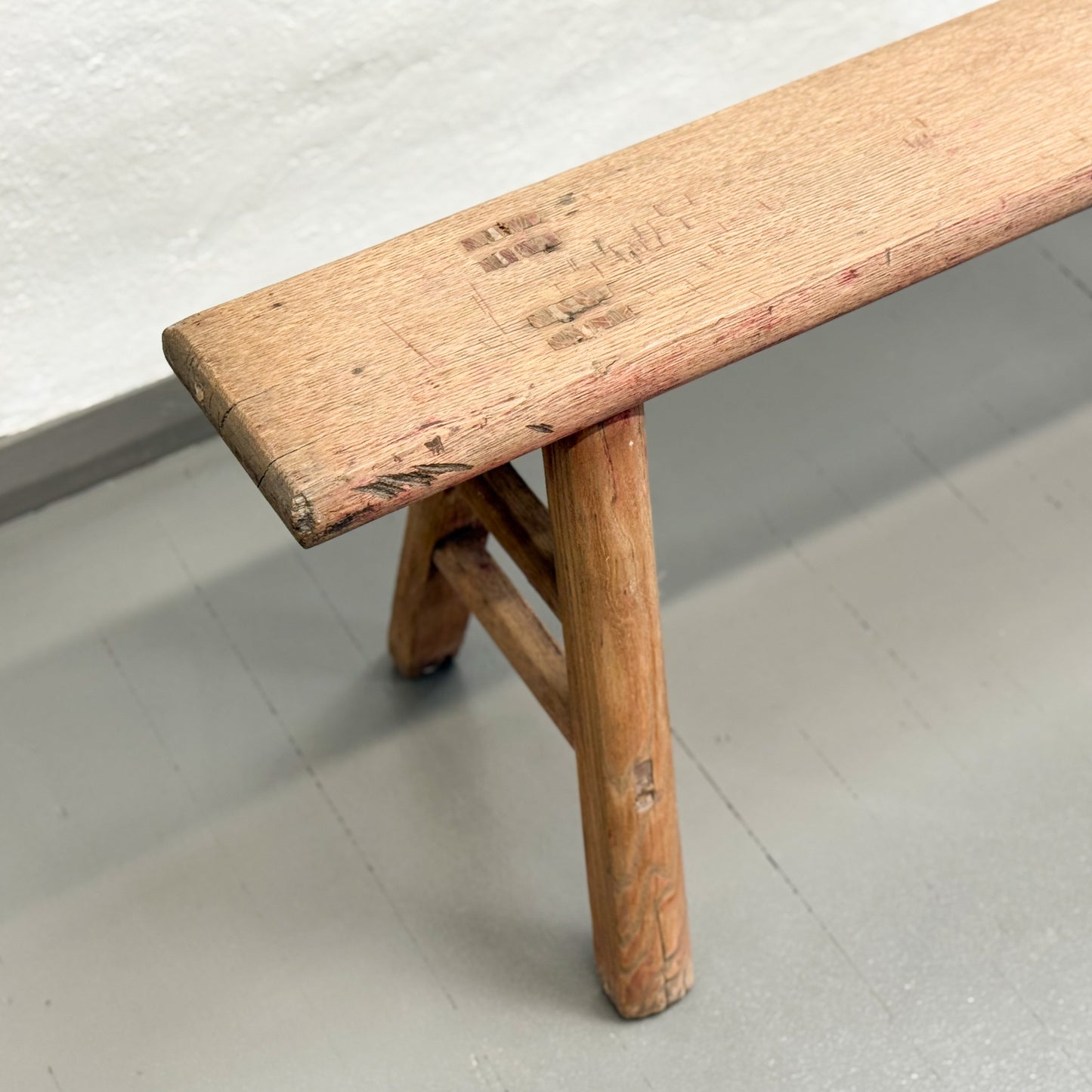 Wooden bench with a worn surface on a plain floor