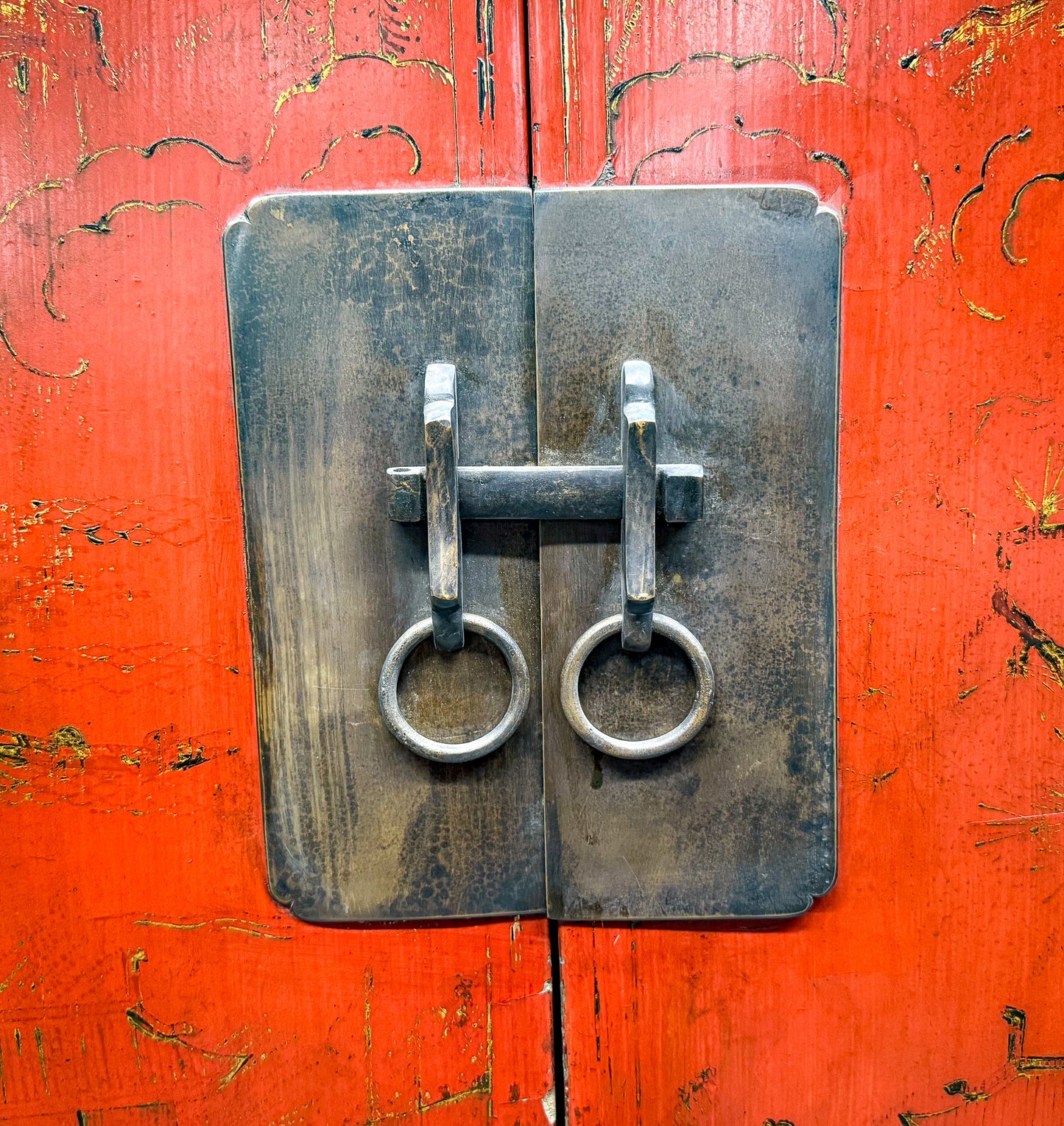 Metal lock on a red wooden door with peeling paint