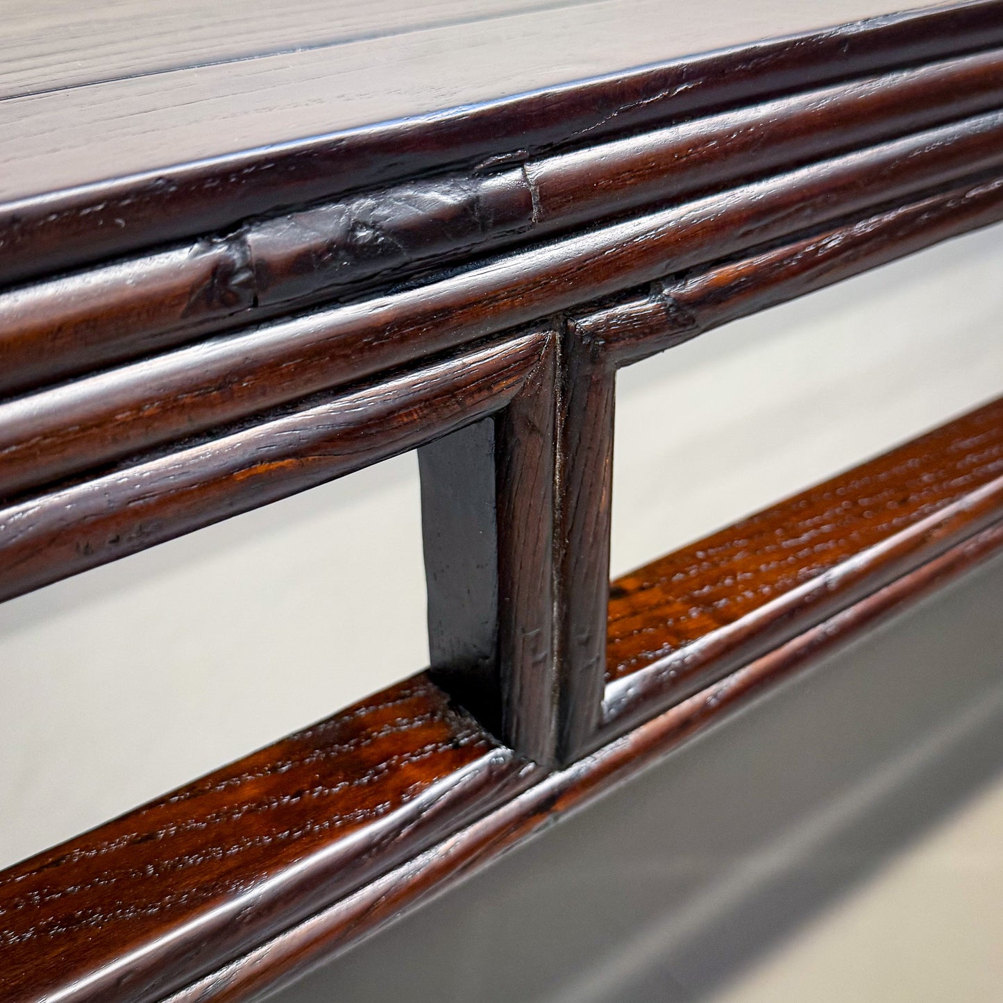 Close-up of a wooden railing with metal brackets on a light background