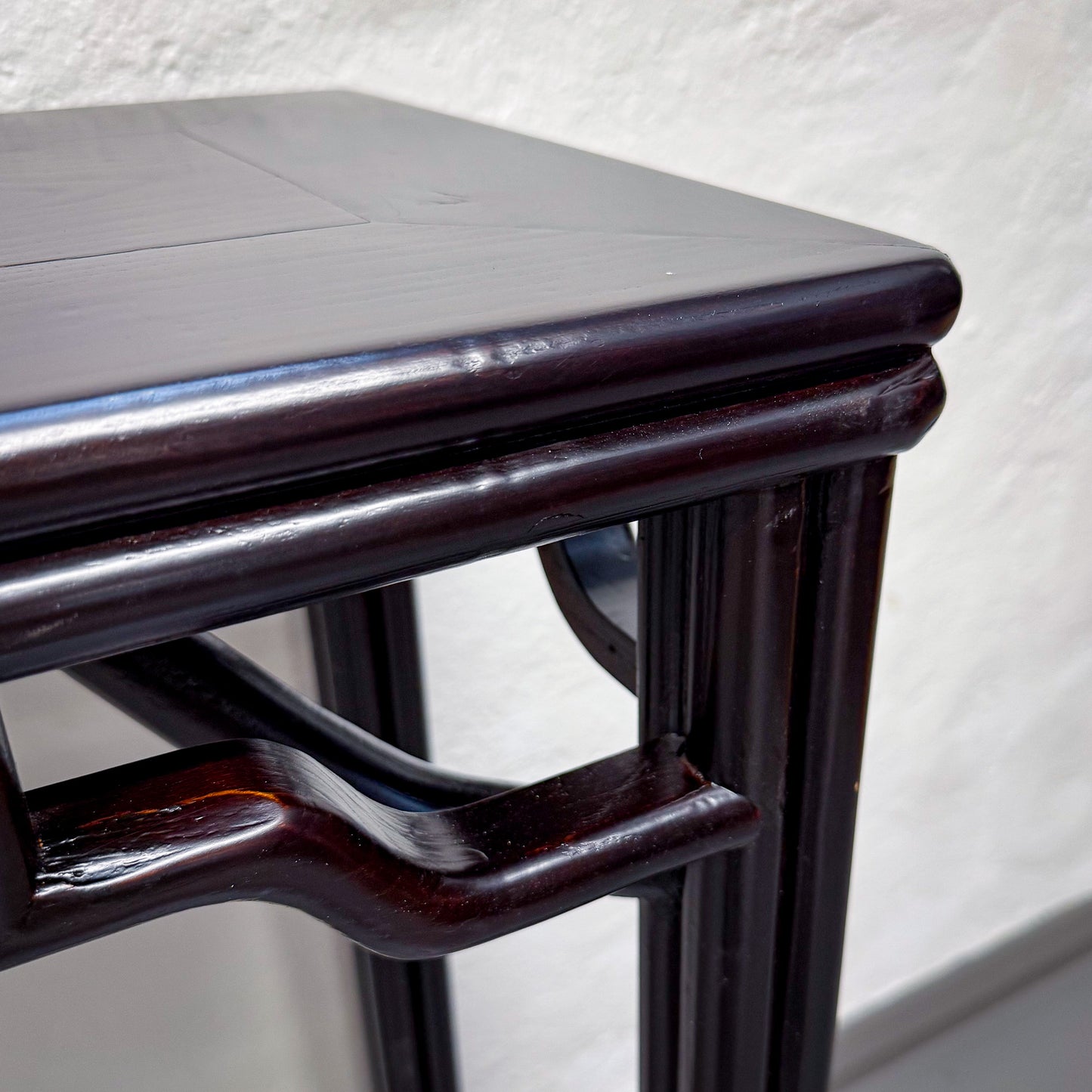 Wooden stool with a dark brown frame and gray seat against a white background