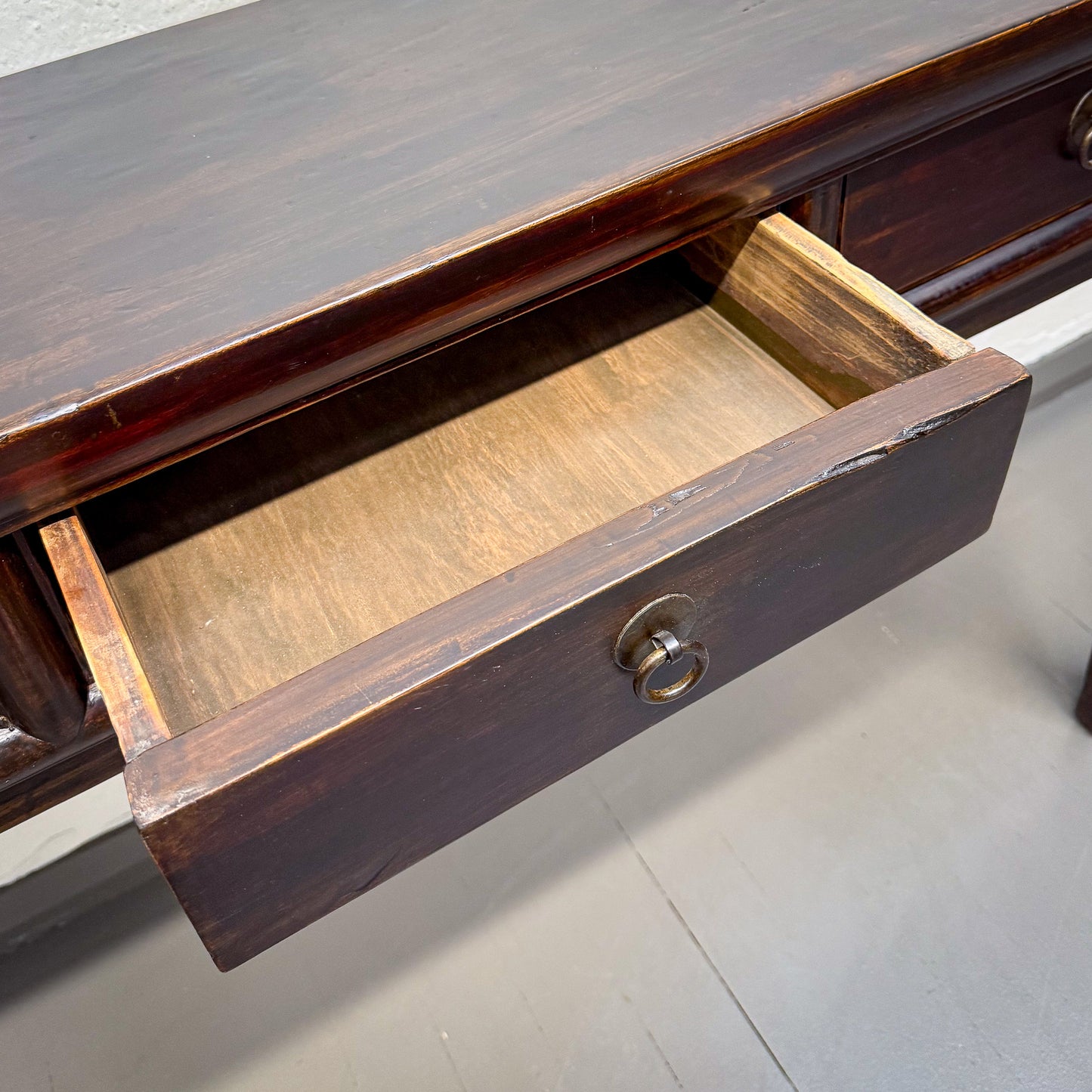 Wooden desk with an open drawer on a gray surface