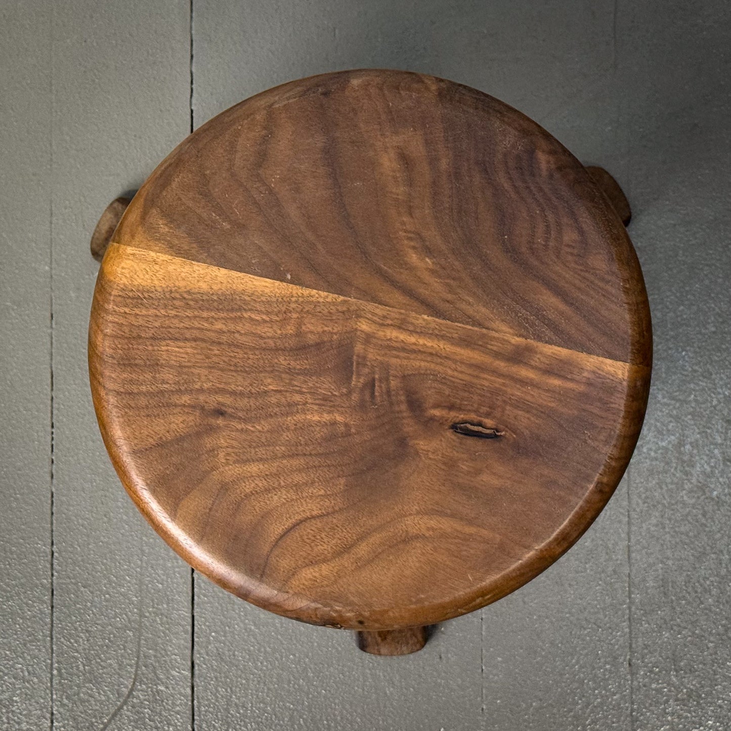 Wooden stool with a dark brown finish on a gray surface