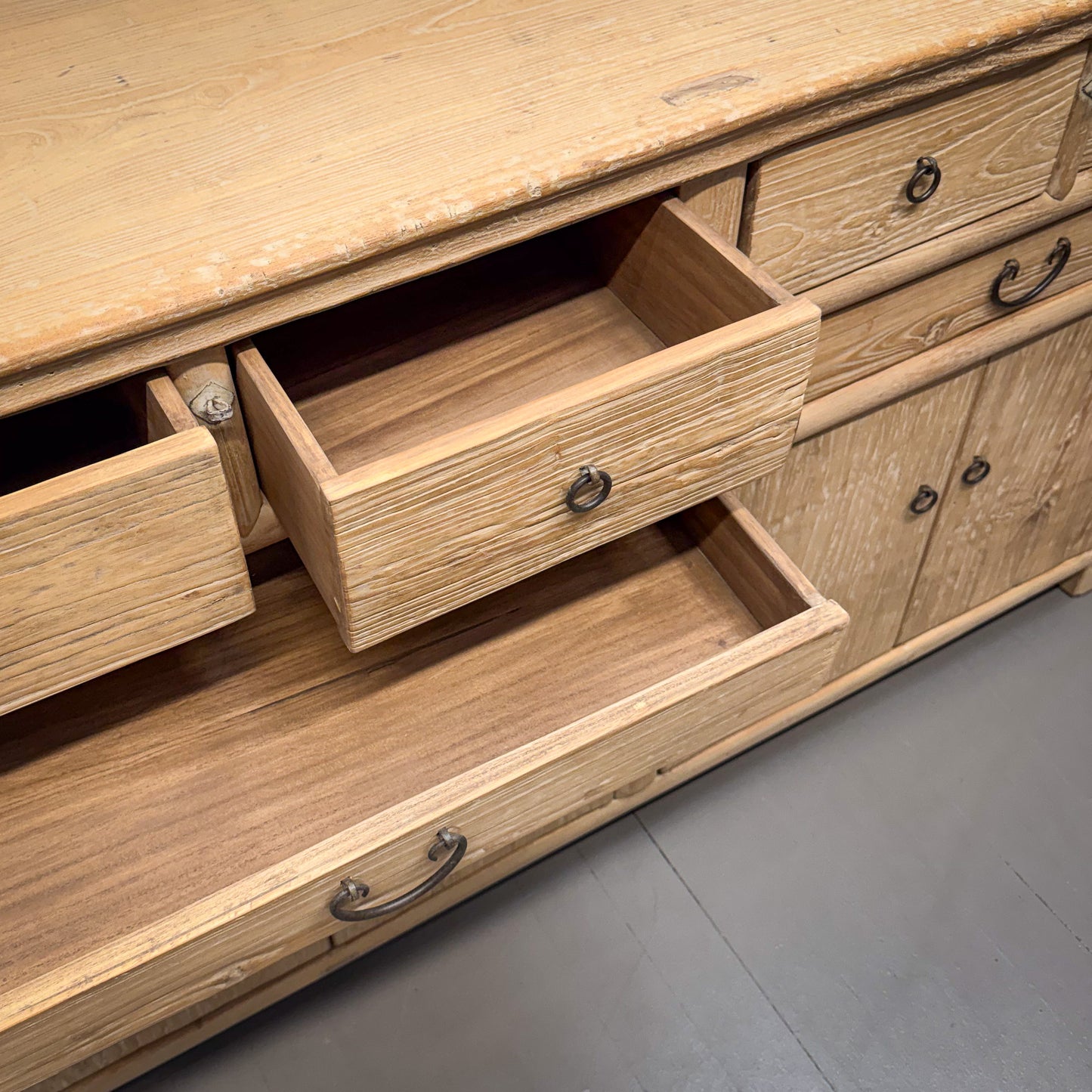 Wooden dresser with open drawers on a gray floor
