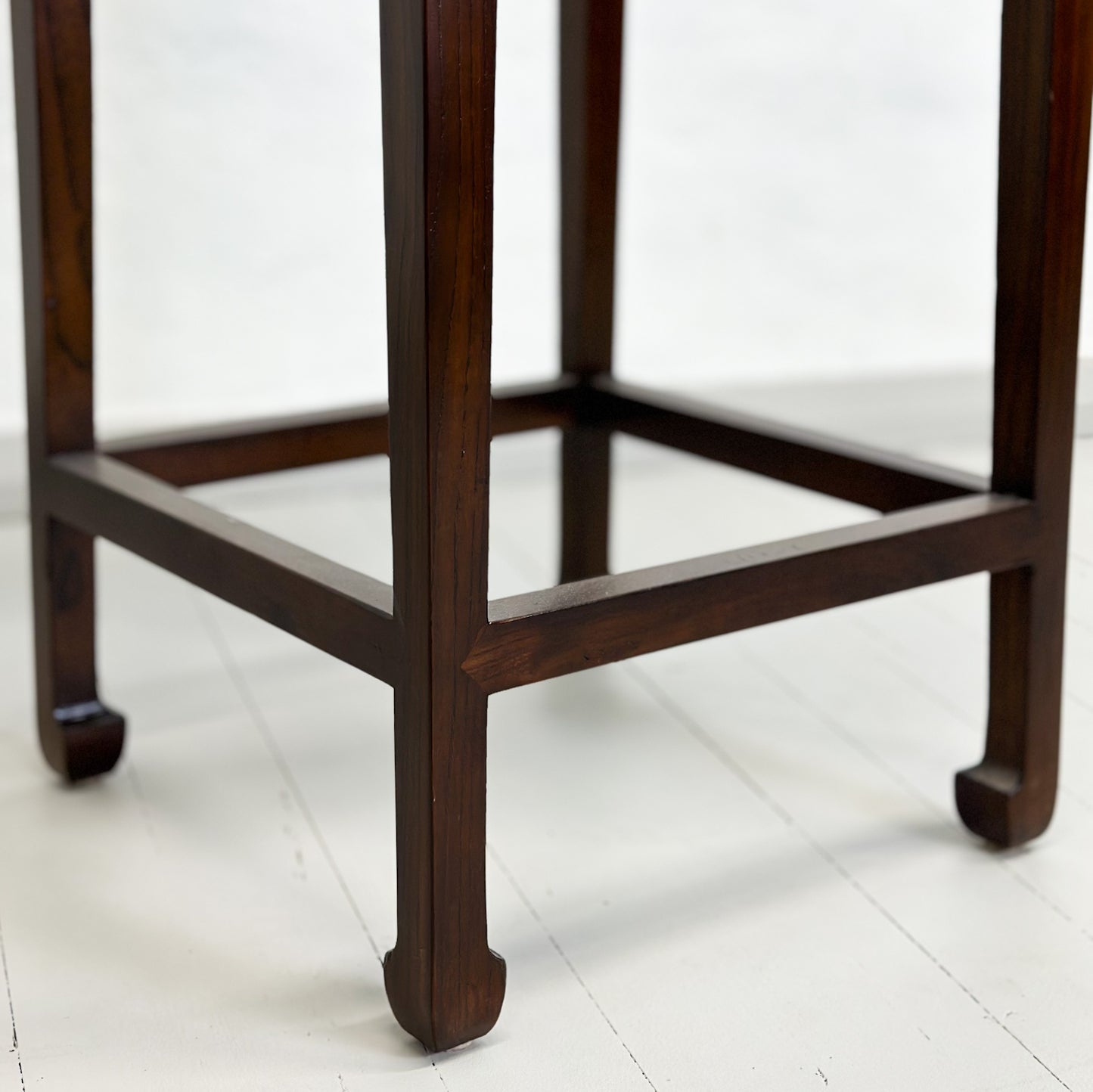 An elegant brown Chinese elm vase table with a bottom stretcher and waisted sides, standing against a plain background.