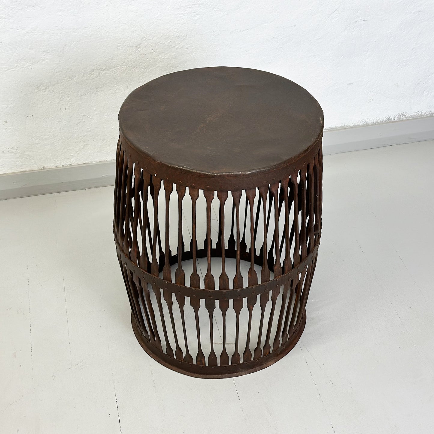A round iron jali drum side table with a geometric pattern, displayed against a neutral background.