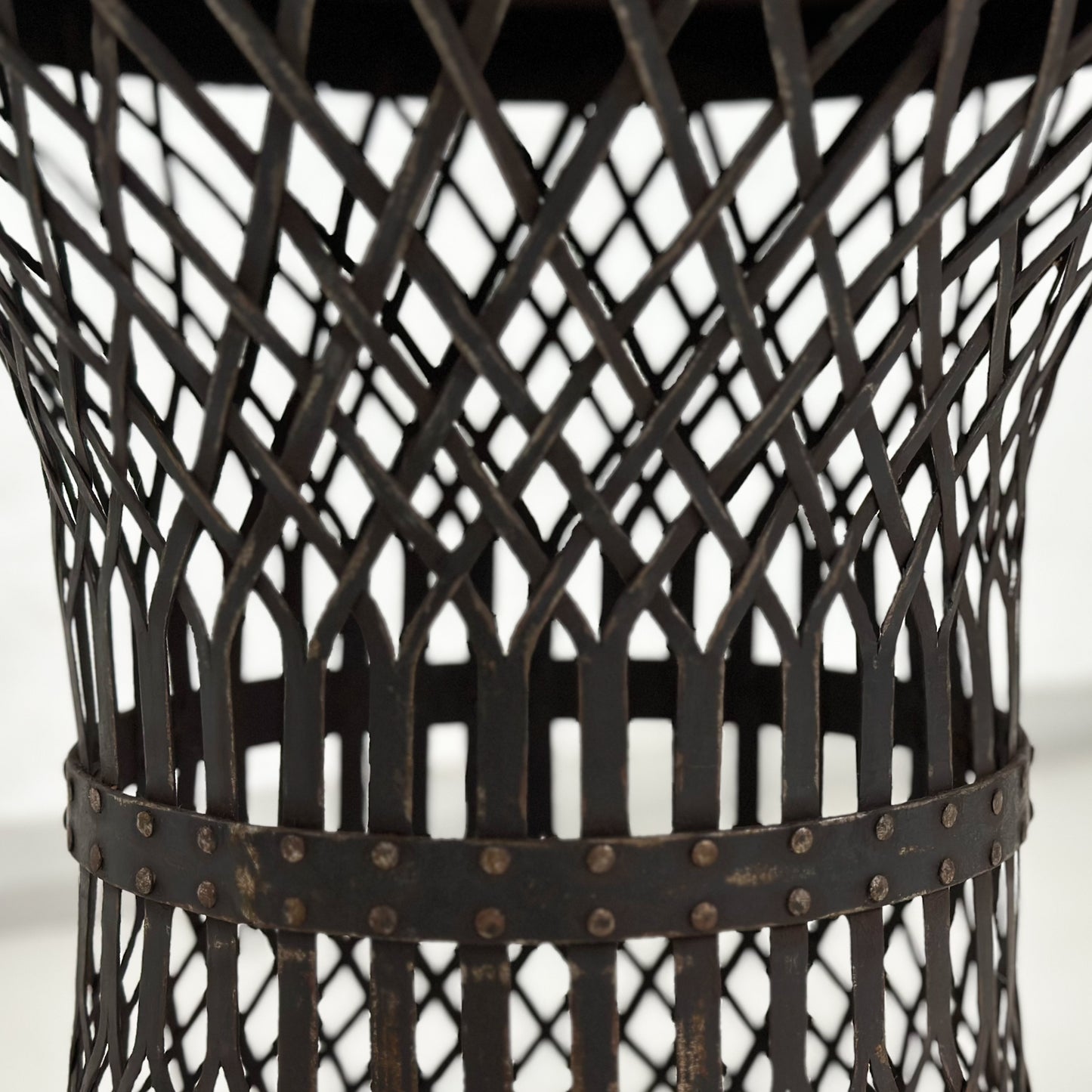 A round iron lattice side table with a dark finish, displayed against a neutral background.