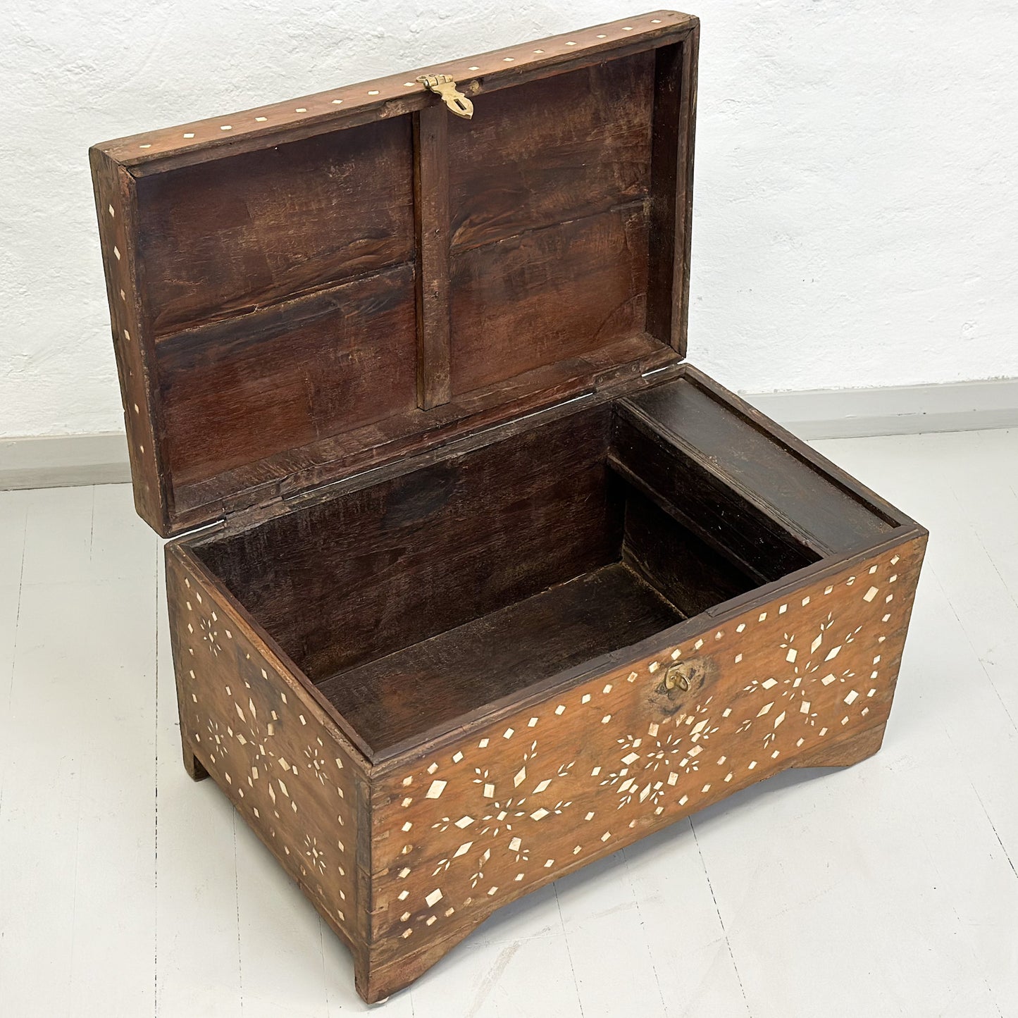 A vintage wooden chest with intricate mother-of-pearl inlay patterns and a metal handle.