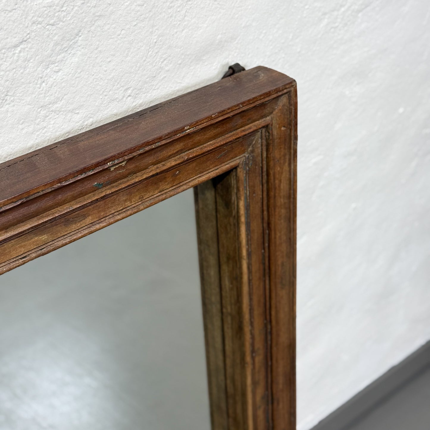 A rectangular vintage teak wood mirror with a plain frame, hanging on a wall.