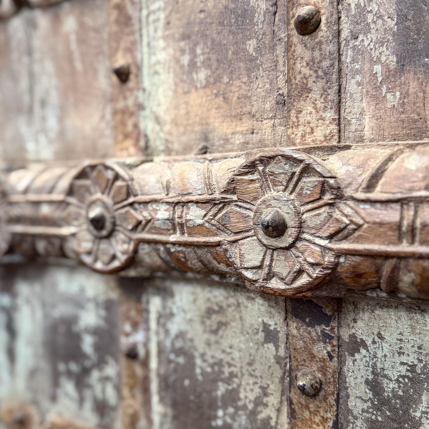 Decorative metal handle on a wooden door with intricate carvings.