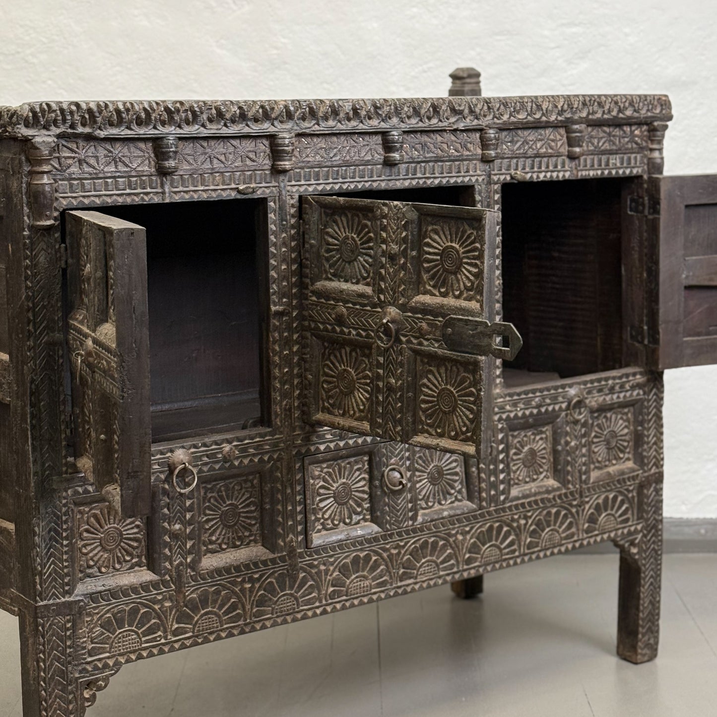 A vintage floral carved wooden chest known as Pitara chest, with a dark finish and intricate hand-carved patterns.